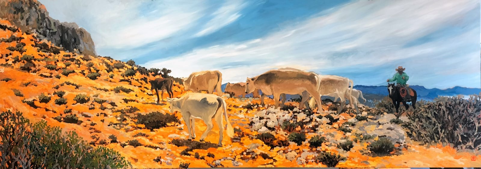 Cattle grazing on a hillside with a person riding a horse, under a blue sky with clouds.