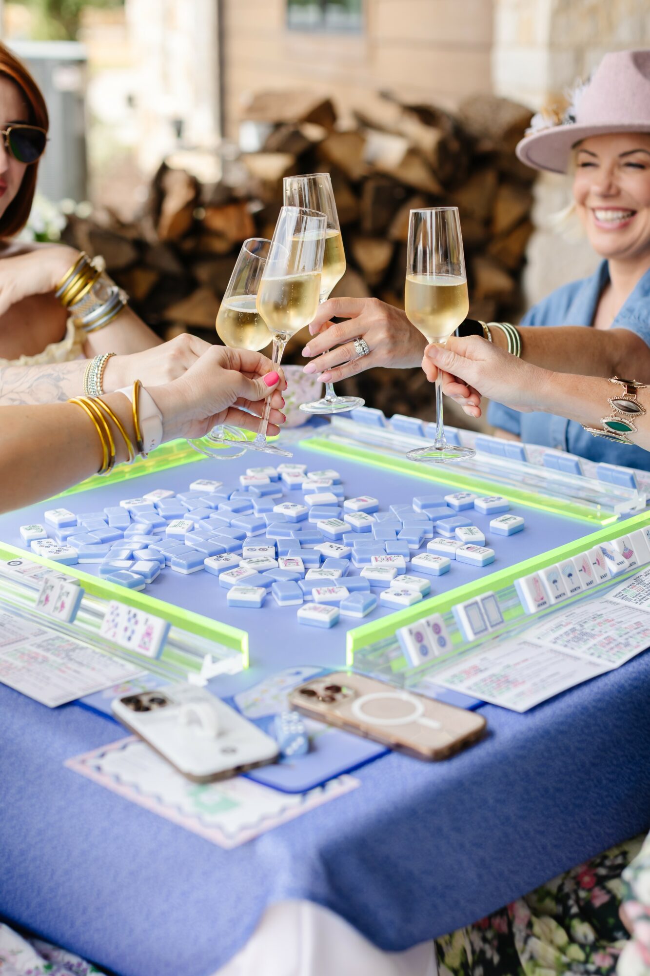 People playing a board game with glasses of champagne, sitting at a table outdoors, smiling and celebrating.