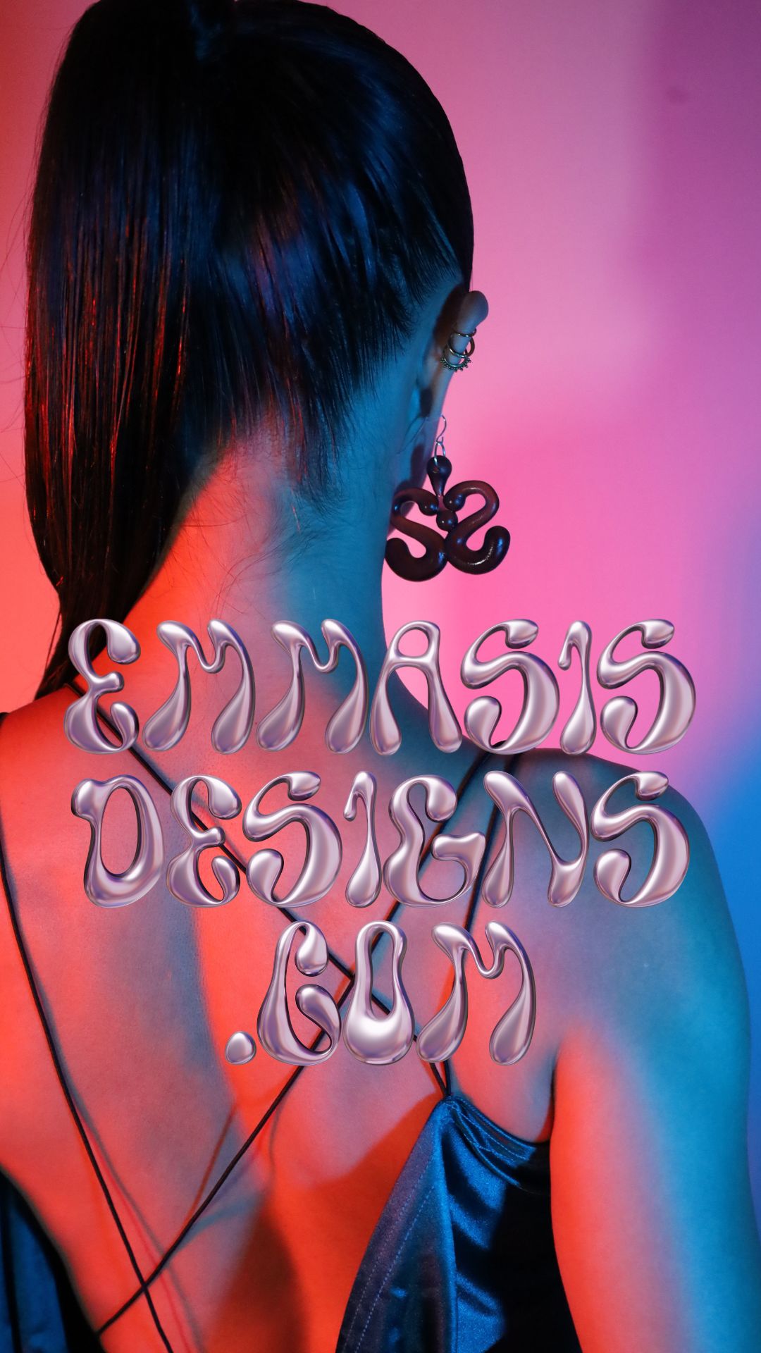 Back of a woman with long dark hair, wearing earrings and a blue top, against a pink background.