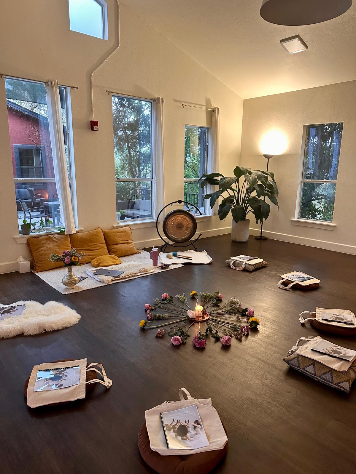 Living room with large windows, a yellow sofa, a potted plant, and decorative items on the floor.