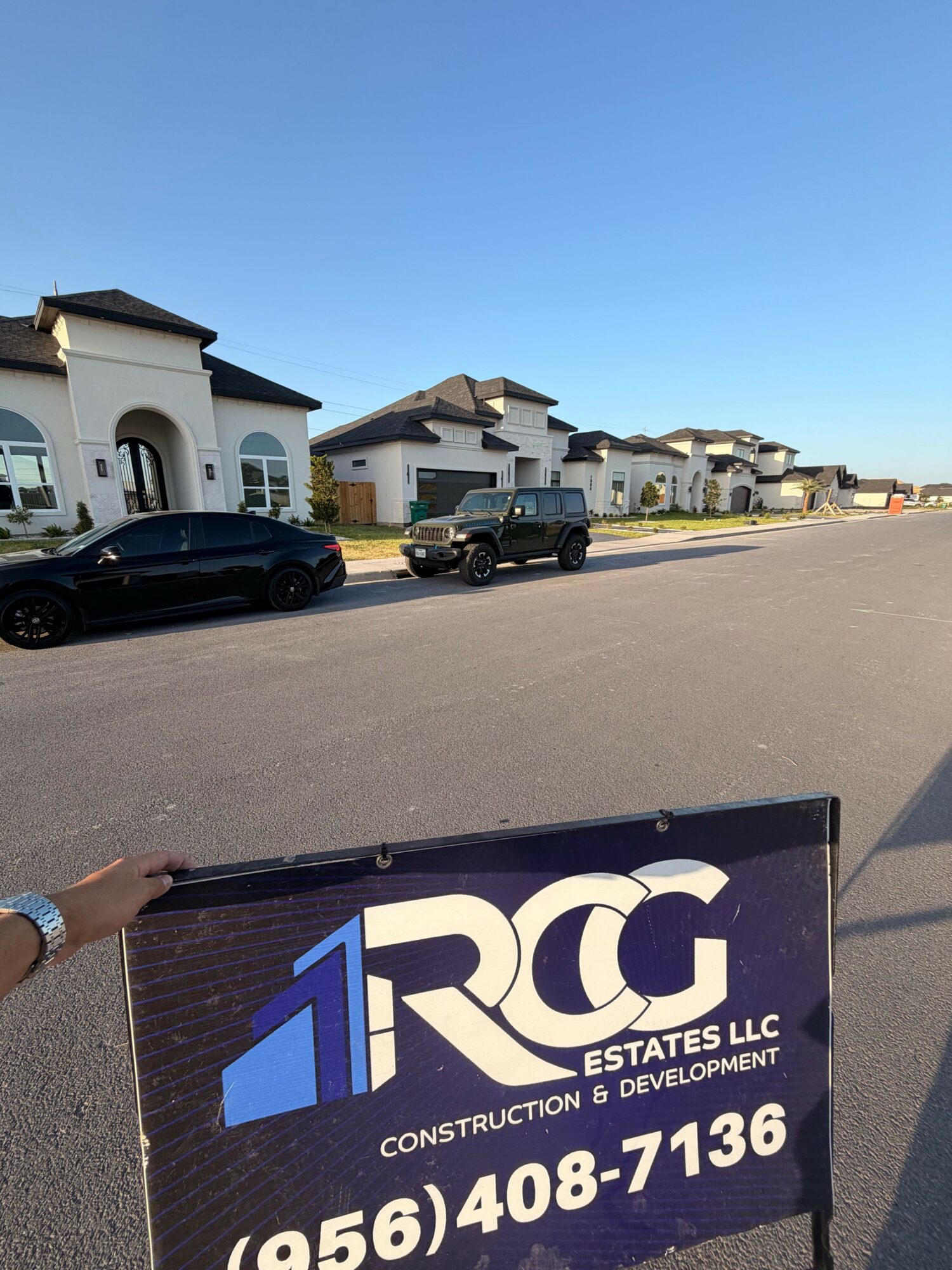 Parking lot with cars and a construction sign for DRC Construction LLC, under a clear blue sky.