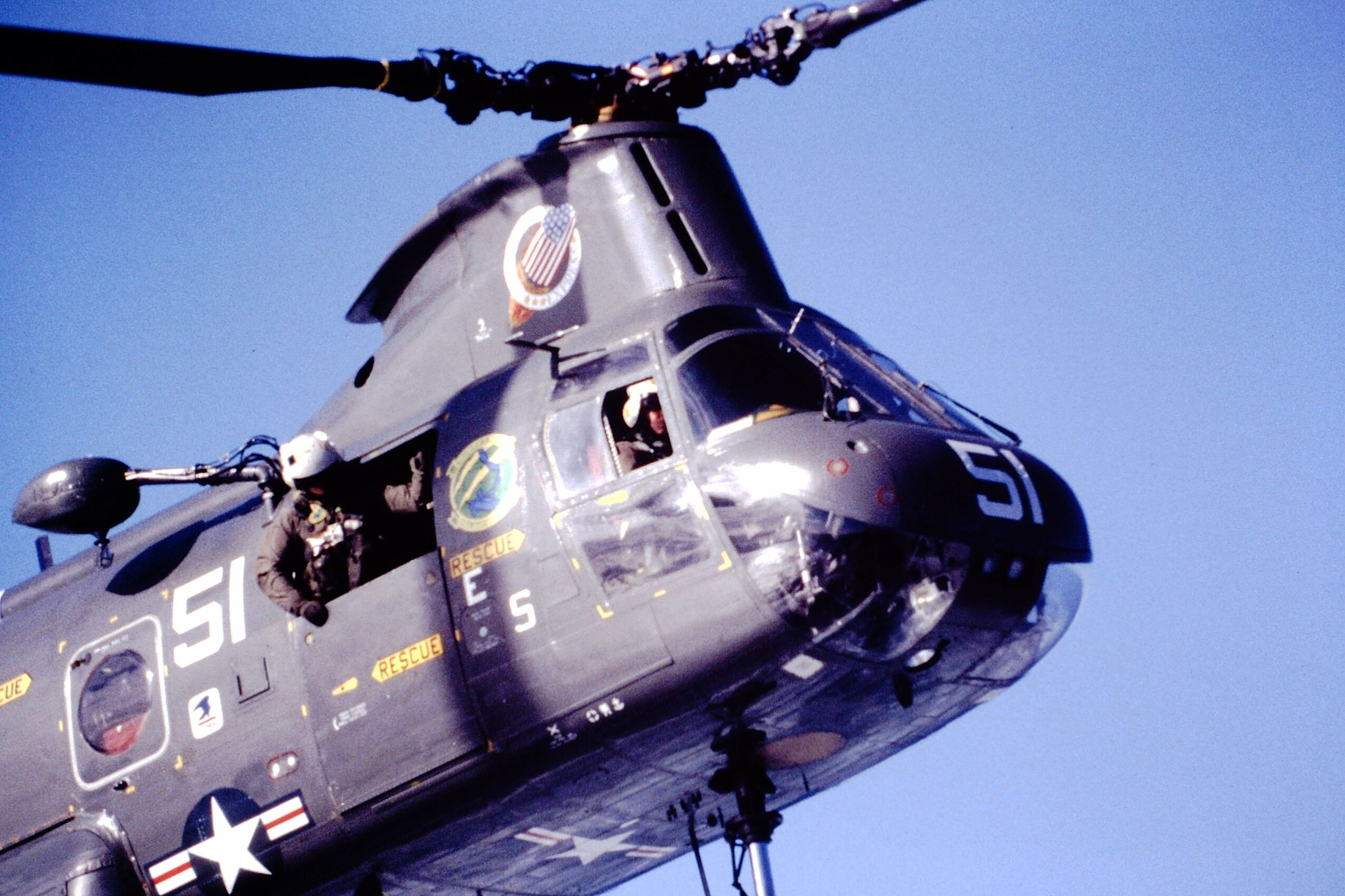 Military helicopter flying in clear blue sky, with visible cockpit and rotor blades, numbered 51.