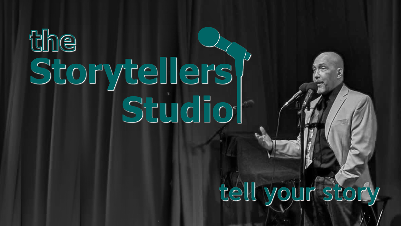 A man speaking into a microphone on stage with a curtain background, with text 'the Storytellers Studio' and 'tell your story'.
