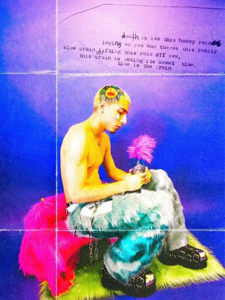 A person with a flower crown sits on a green surface, holding a pink feathered object, against a purple background with handwritten text.