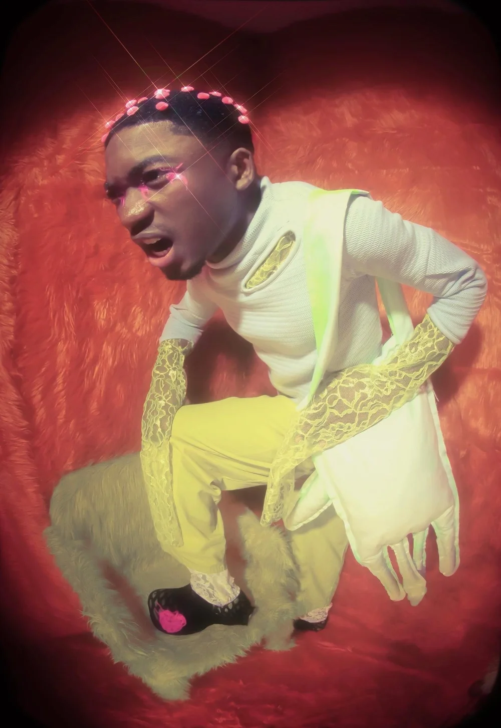 Person with makeup and costume, kneeling on a furry surface, against a red background.