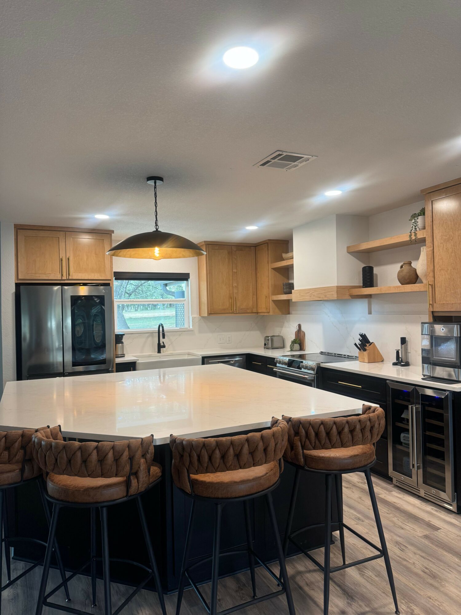 Kitchen with bar stools, a black countertop, and a view through a glass door to the outside.