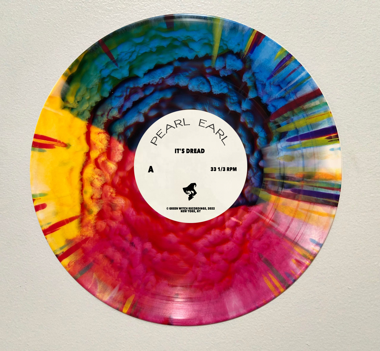 Colorful vinyl record with a white label in the center, mounted on a light-colored wall.