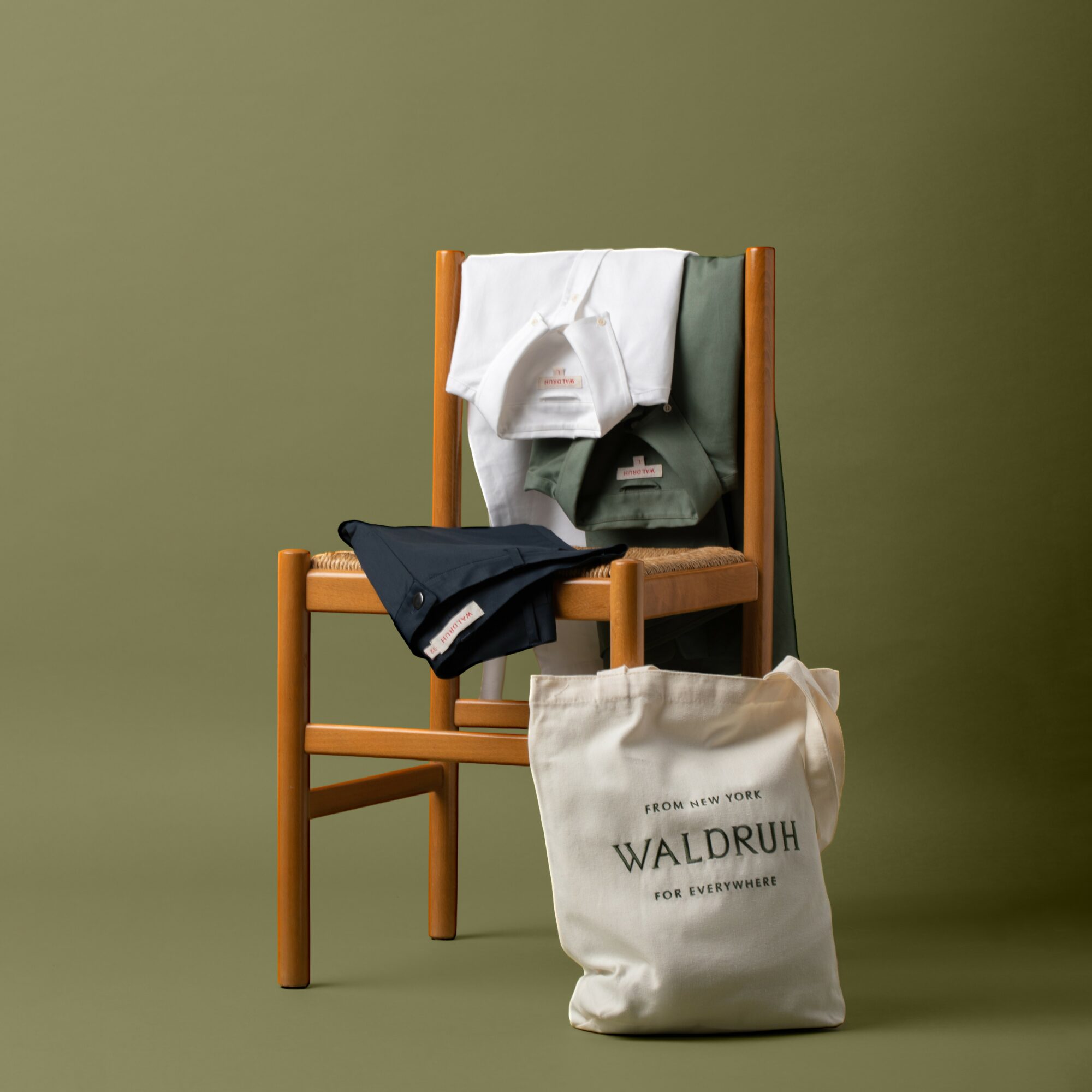 Chair with clothes and a bag against a green background.