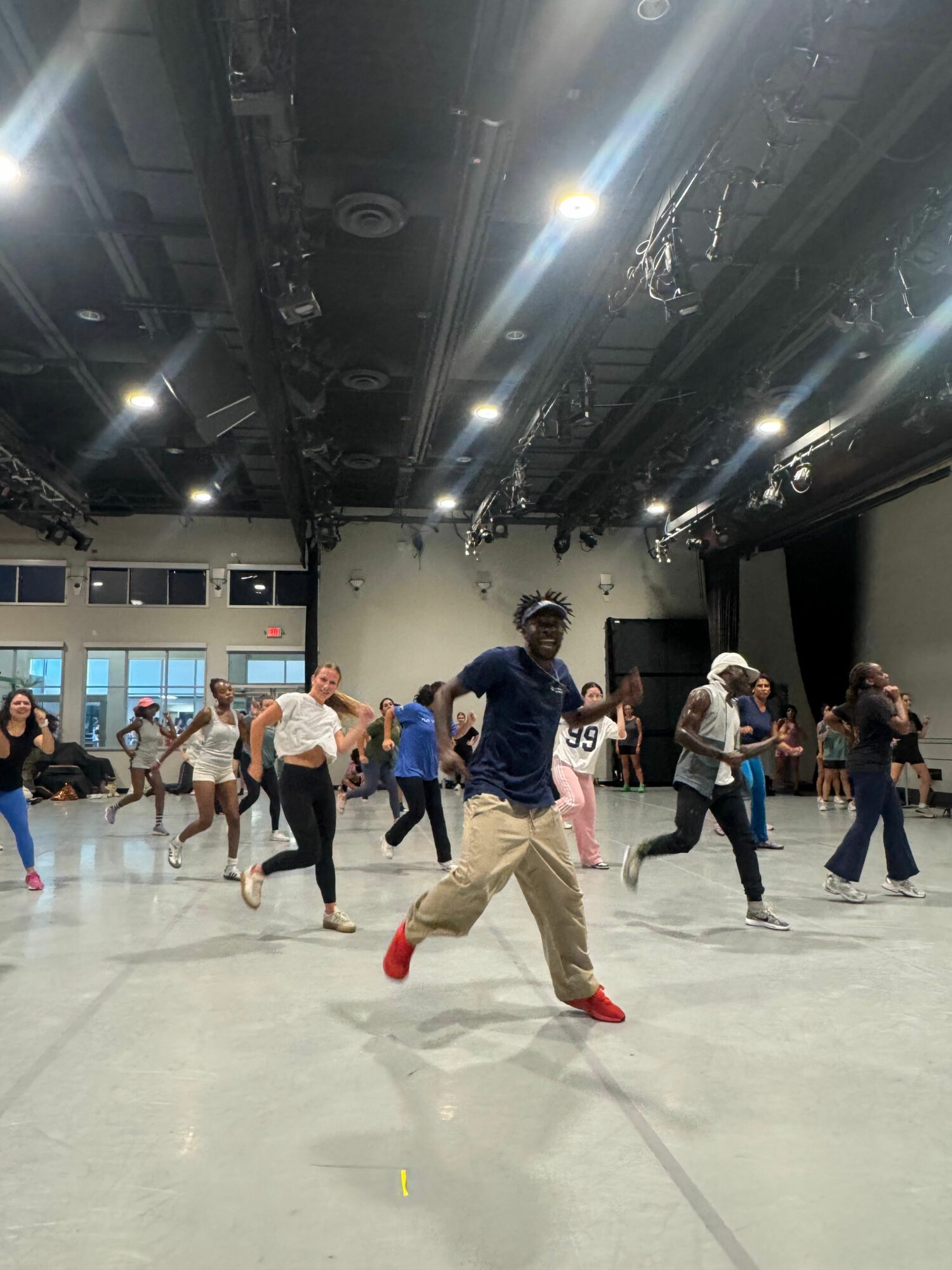 Group of people dancing in a spacious indoor venue with high ceilings and bright lighting.