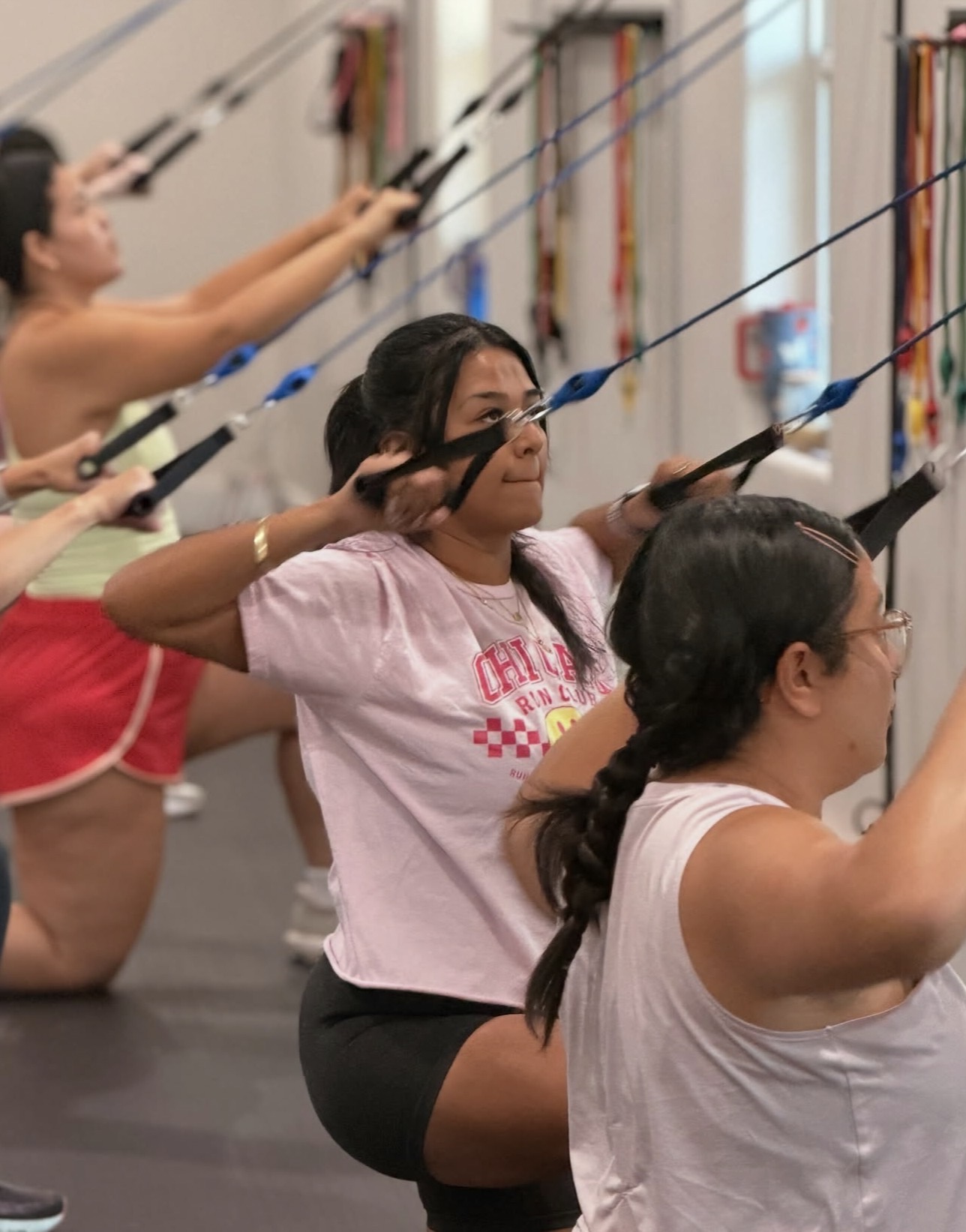 Group of women practicing yoga with resistance bands in a studio, focusing on stretching and balance.