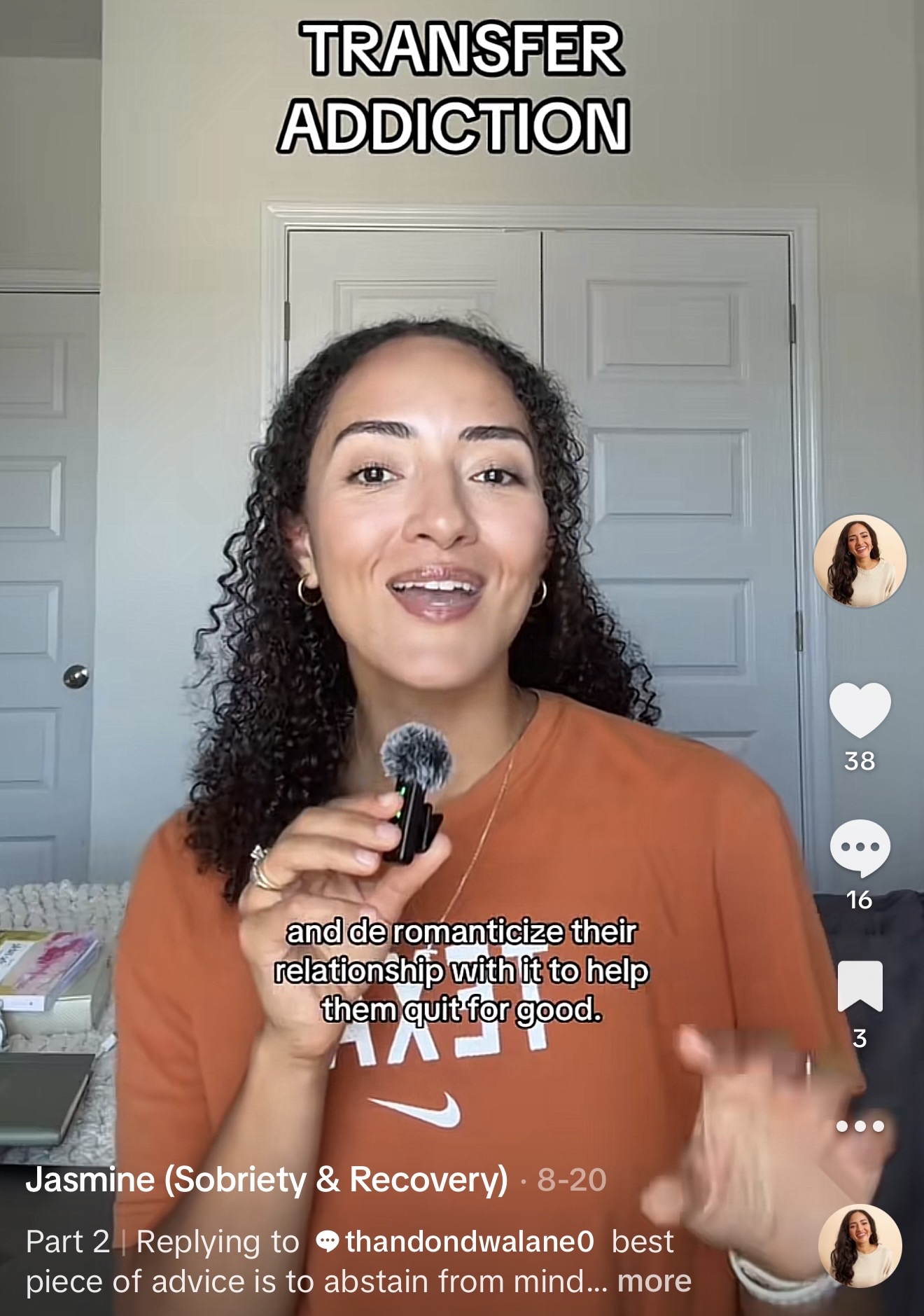 Woman with curly hair holding a microphone, smiling, wearing an orange shirt, standing in front of a door, text overlay about addiction.