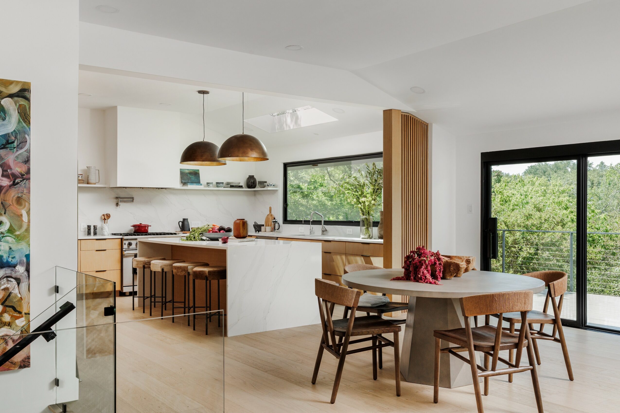 Open kitchen and dining area with large window and sliding glass door, modern furniture, and natural light.