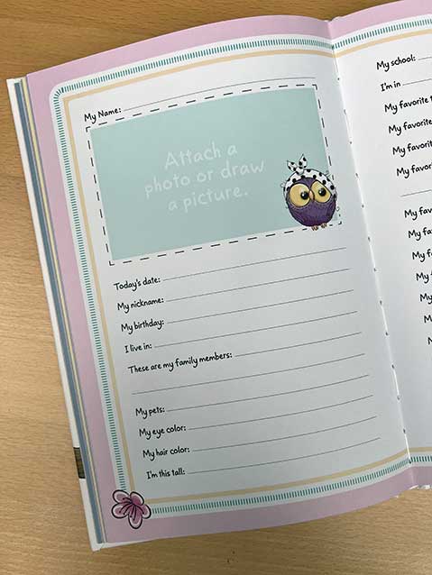 Open notebook with a page for drawing and writing, decorated with a bee and a flower, on a wooden surface.
