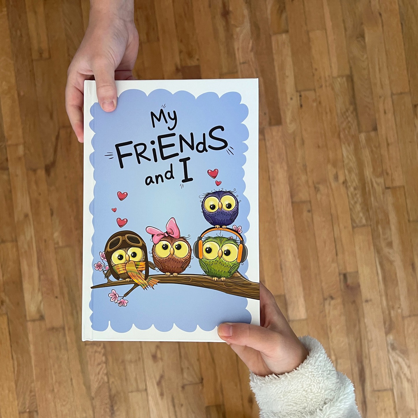 Two hands holding a card with four cartoon owls sitting on a branch, surrounded by hearts, with the text 'My friends and I'.