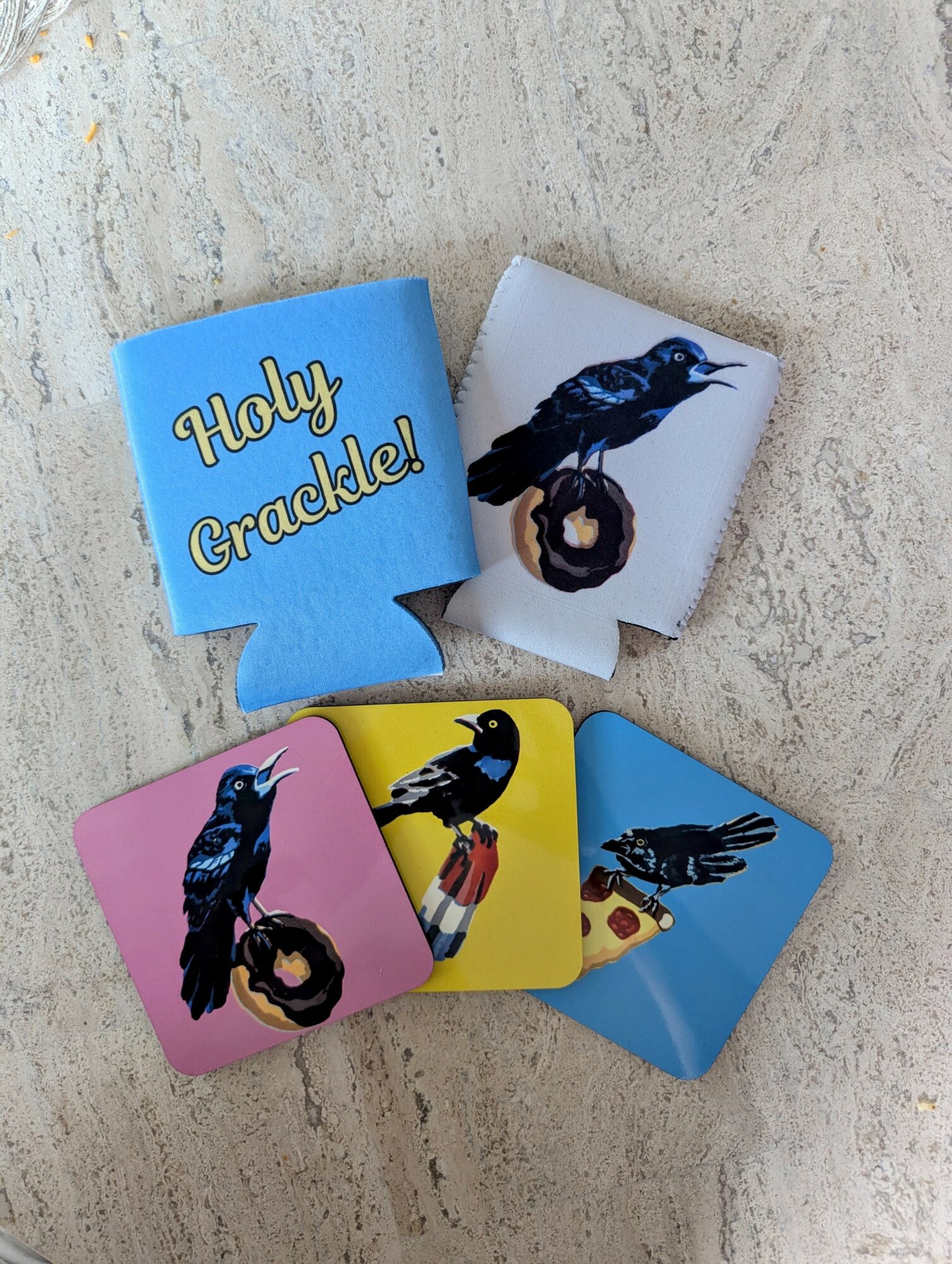 Five small paper cups with colorful designs and text, arranged on a textured surface.