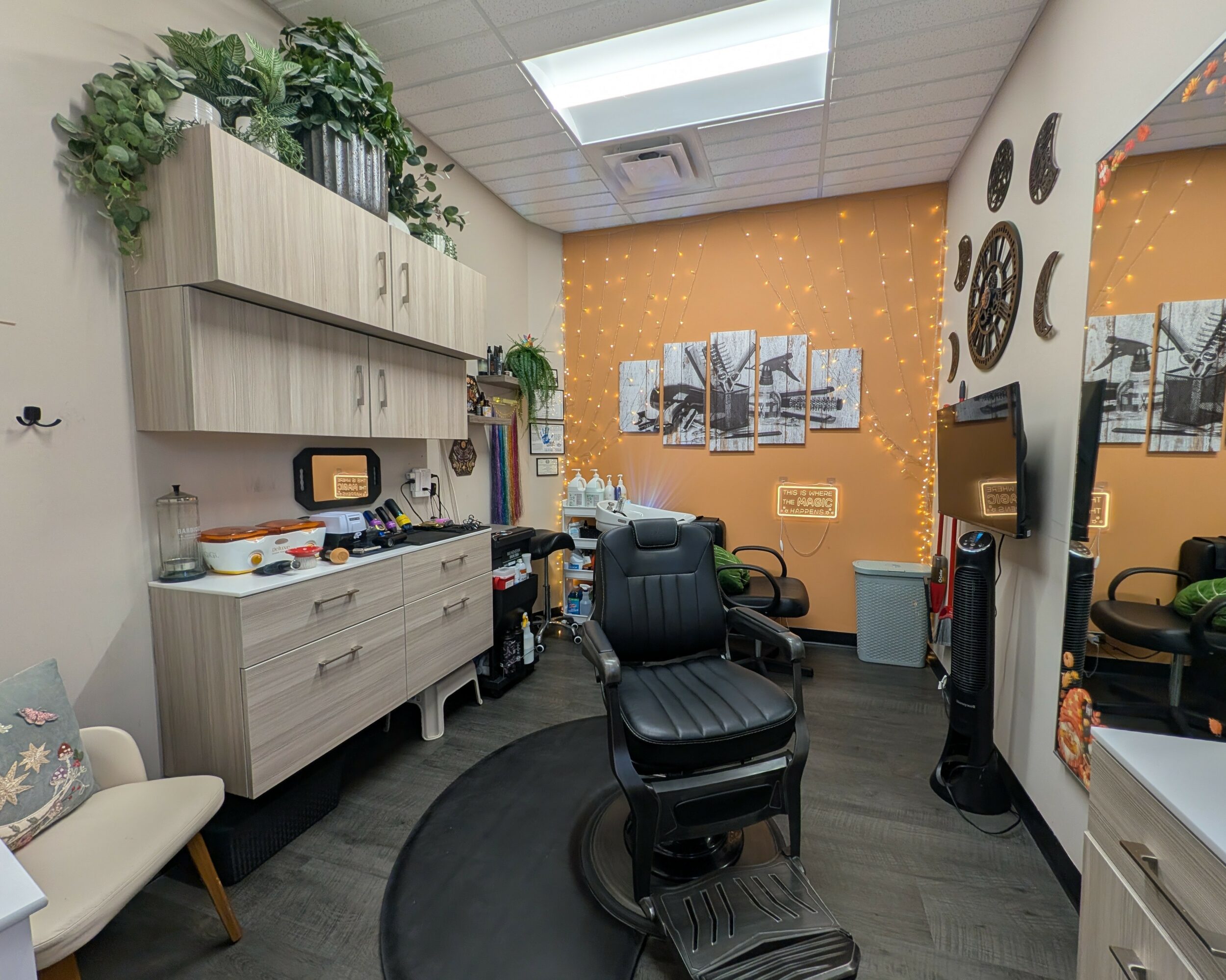 Office room with a black chair, orange wall, shelves, and a mirror, illuminated by a skylight, with various decorations and equipment.