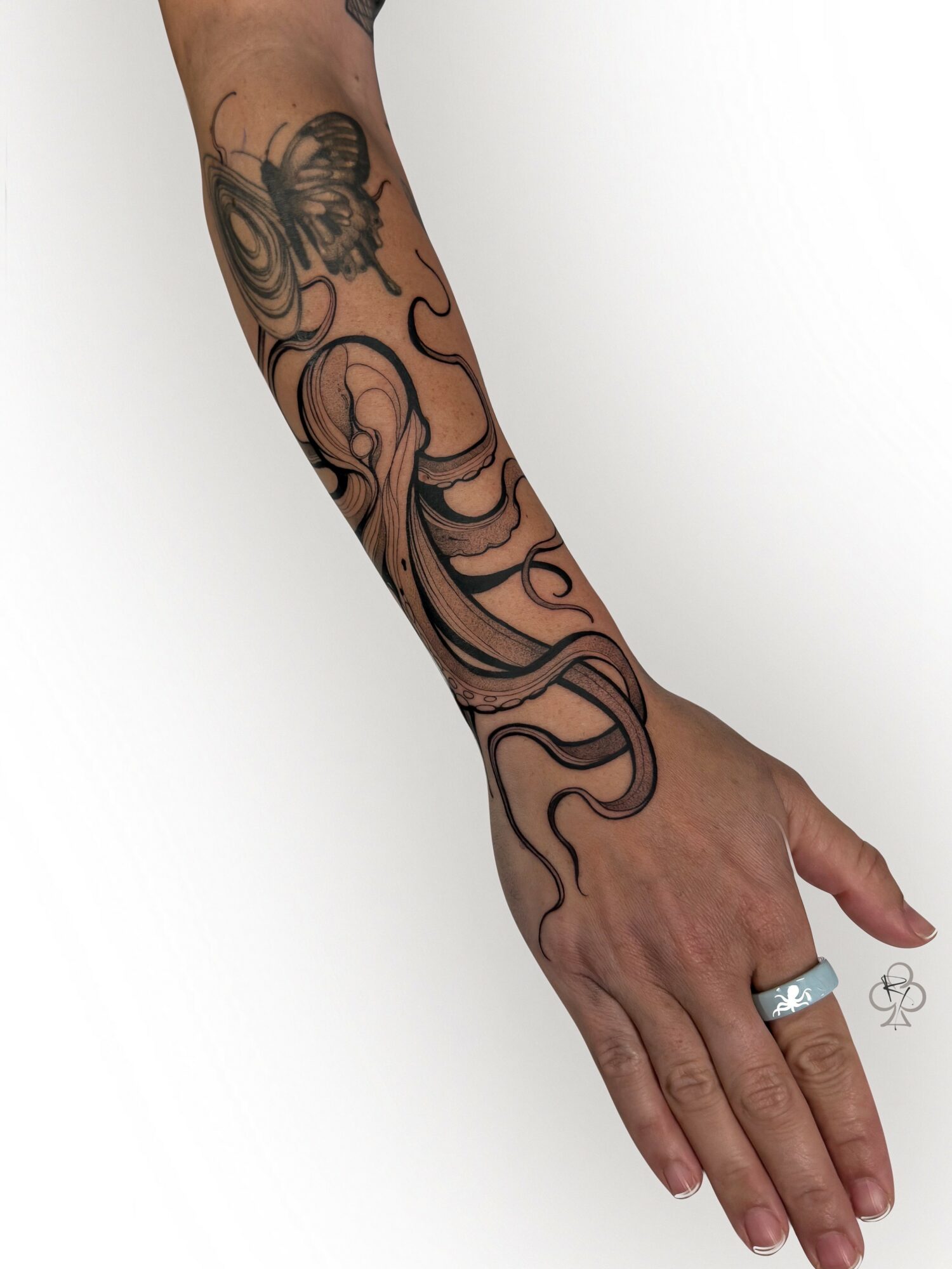 A tattooed arm with swirling black ink design extending from the wrist to the upper arm, against a plain white background.