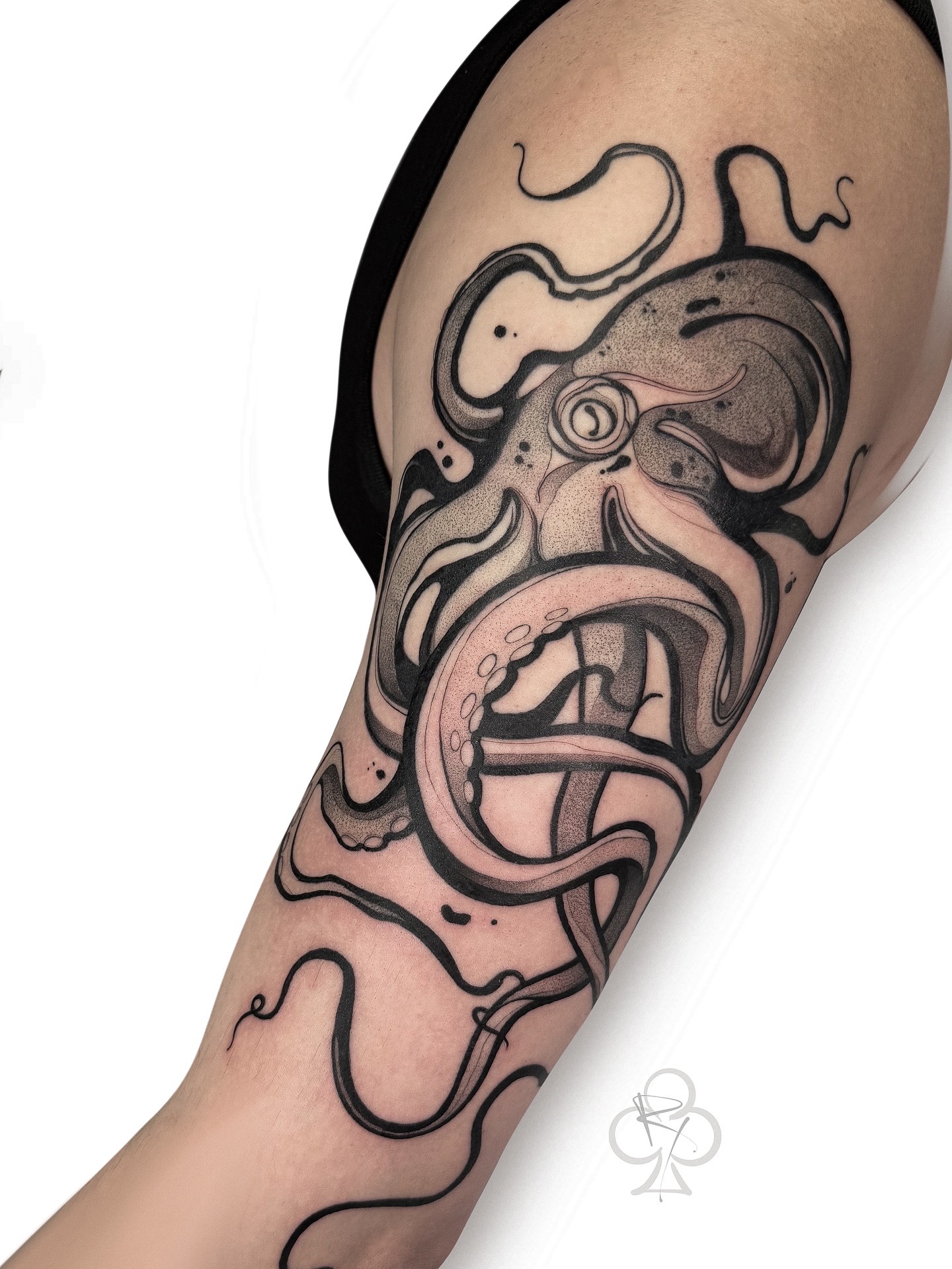Tattoo of a stylized face with tentacles and a tongue on a person's arm.