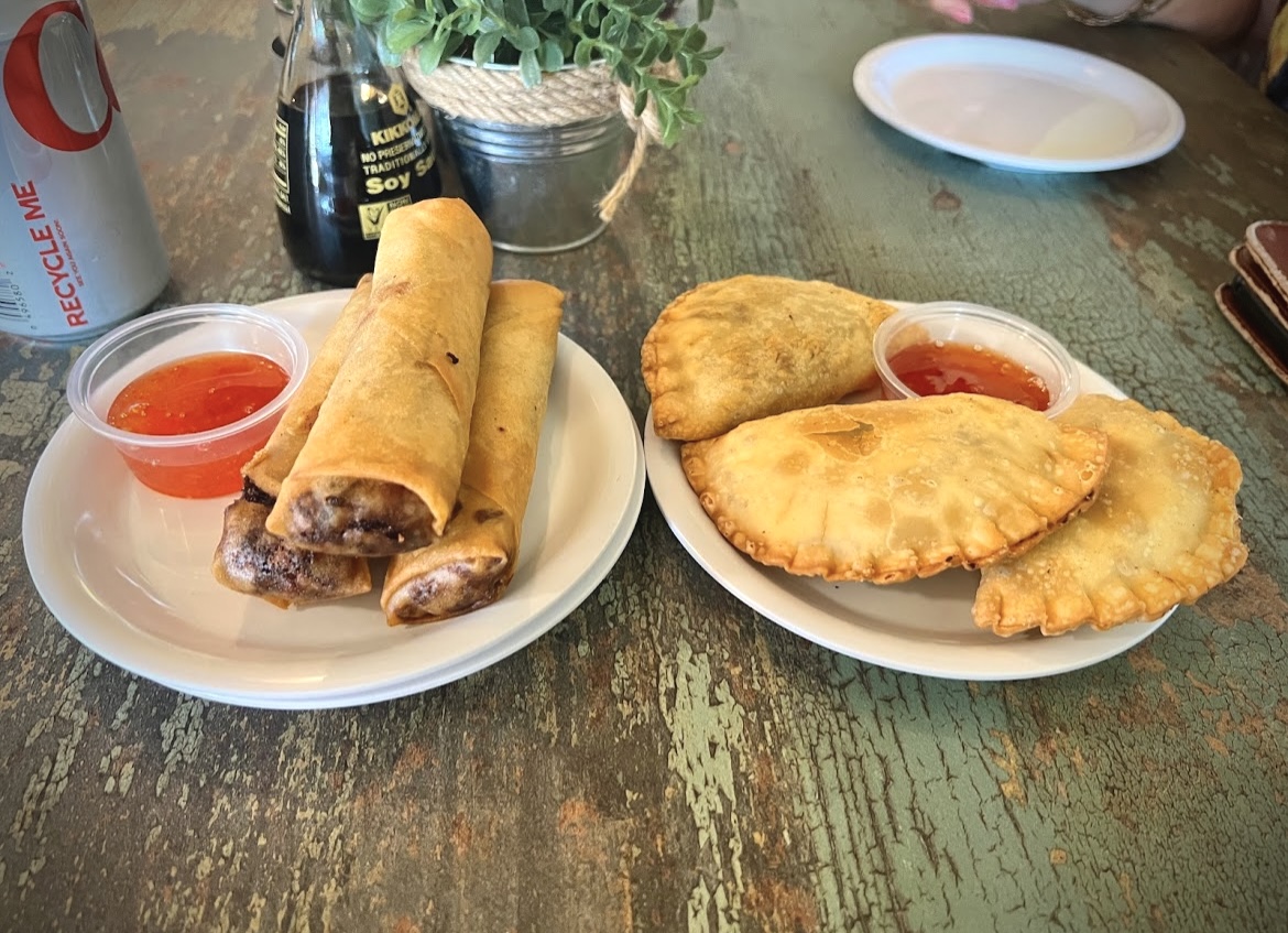 Two plates of food on a table, one with spring rolls and dipping sauce, the other with fried pastries and sauce.