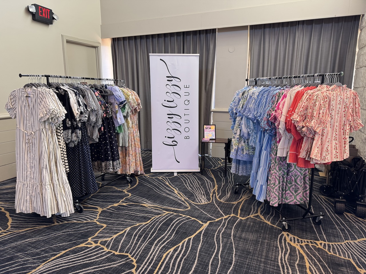 Clothing racks with dresses and tops in a boutique, with a sign reading 'Luxury Closet BOUTIQUE' in the background.