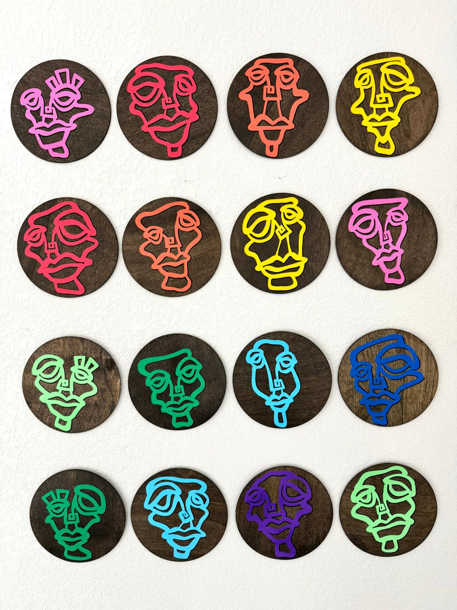 Four rows of colorful face illustrations on black circular backgrounds, each with different facial expressions and colors.