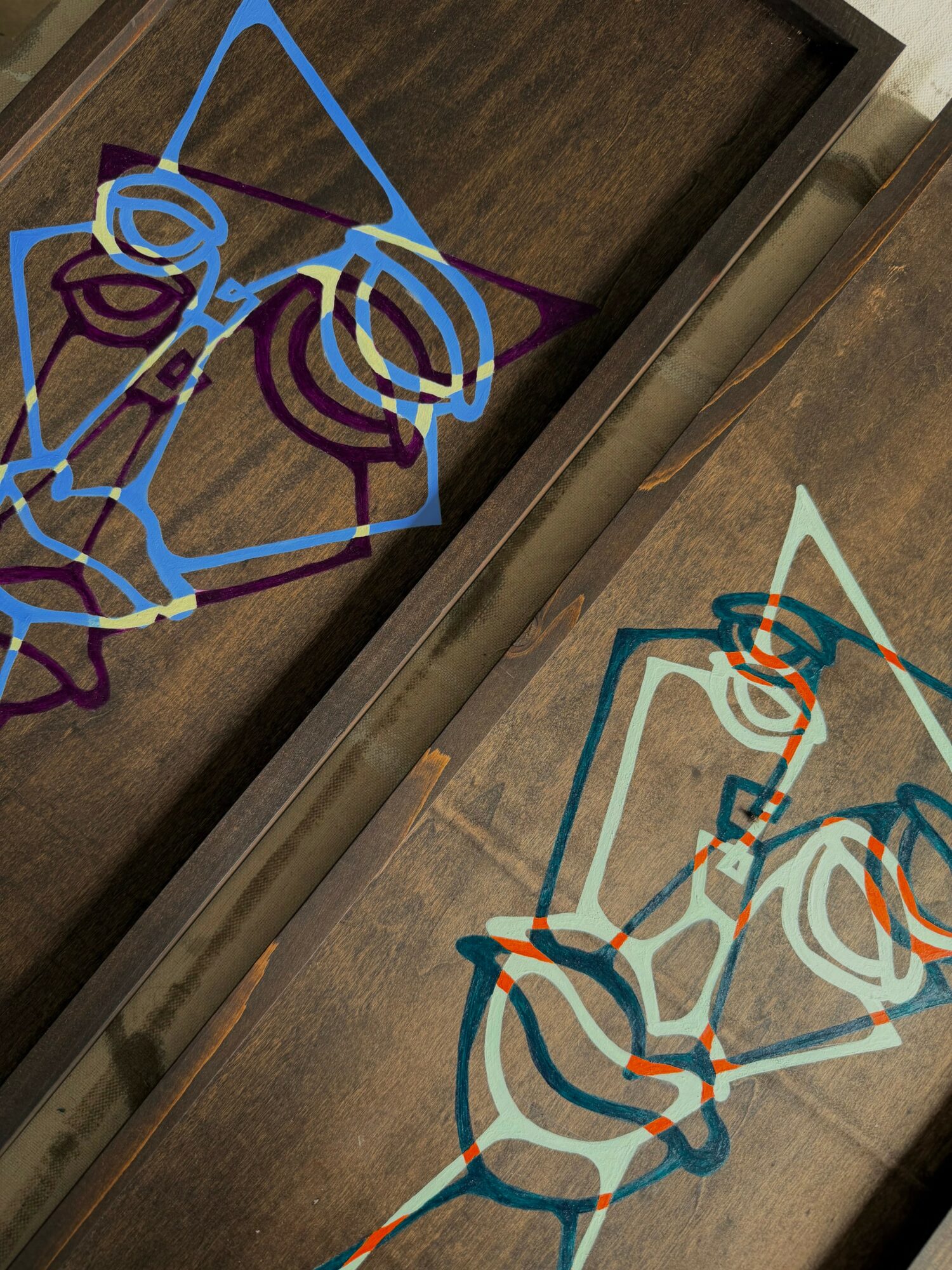 Colorful abstract line drawing of a person with glasses, sitting and holding a phone, on a wooden surface.