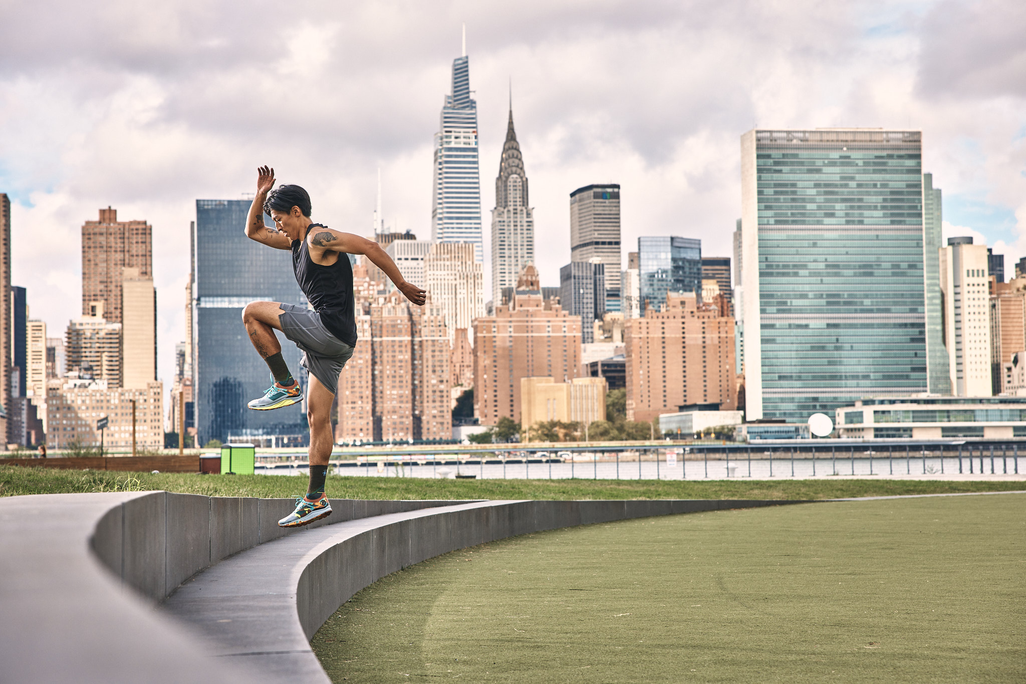 A person jumps on a curved track with the Manhattan skyline in the background.