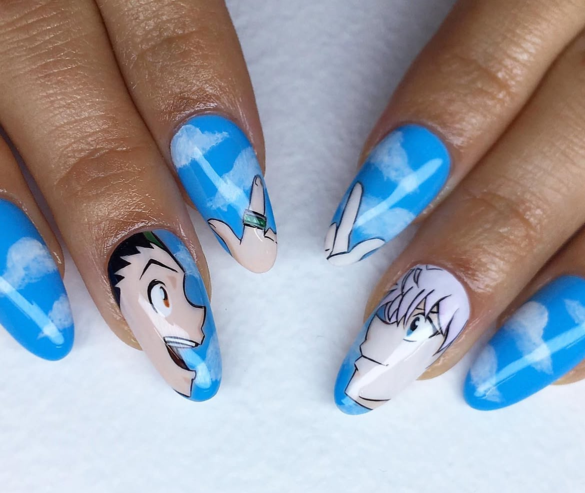 Nail art with blue sky and white clouds, featuring anime-style character faces on two nails, with a black and white face on one nail and a white-haired face on another.