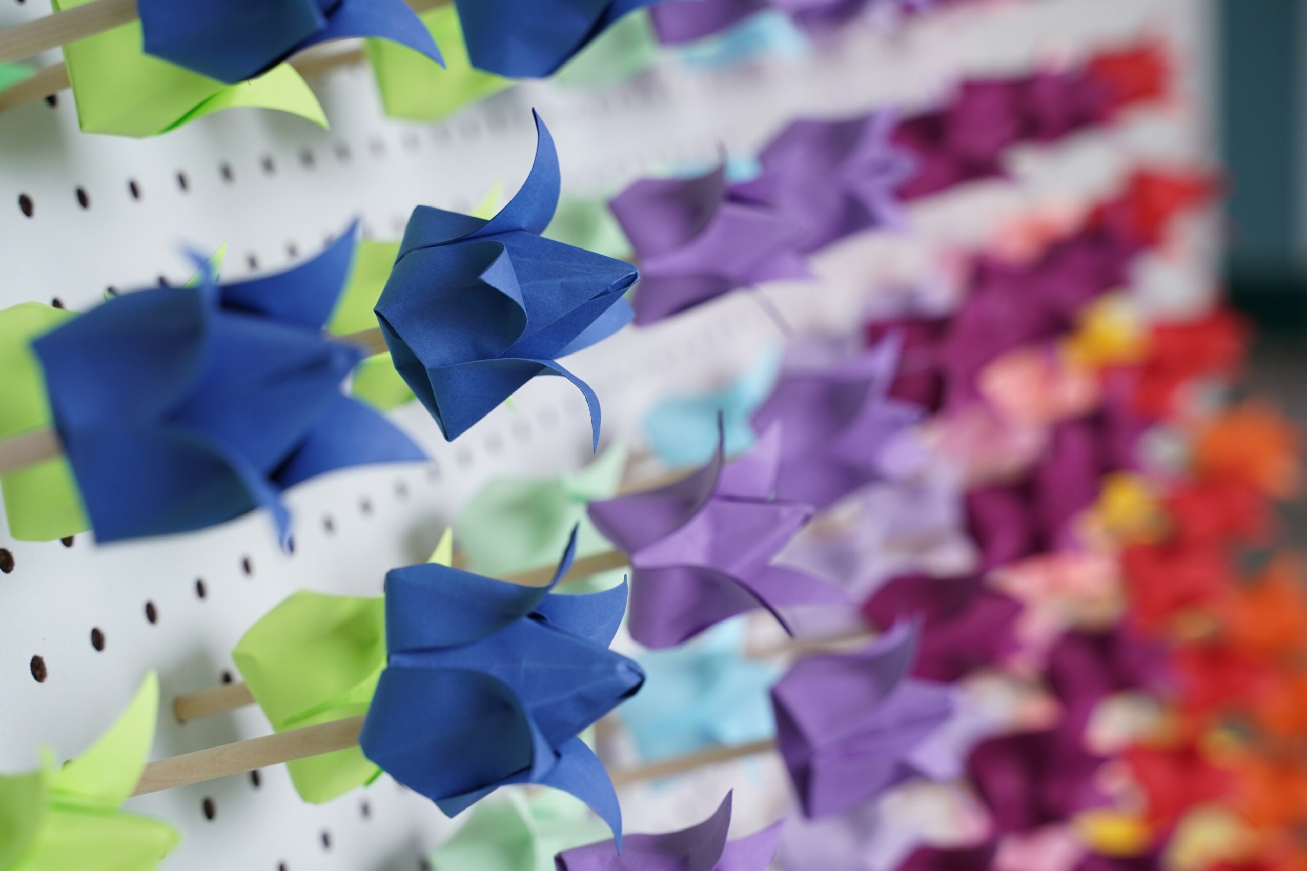 Colorful paper umbrellas hanging on a display, arranged in rows with various colors including blue, purple, pink, and orange.