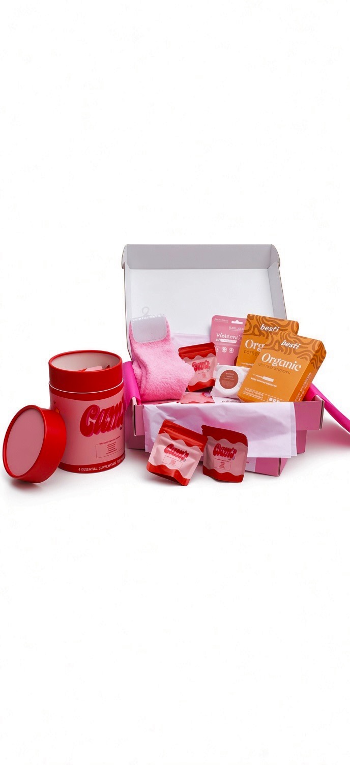 Open box with pink and orange items, red container, and small packages inside, on a white background.