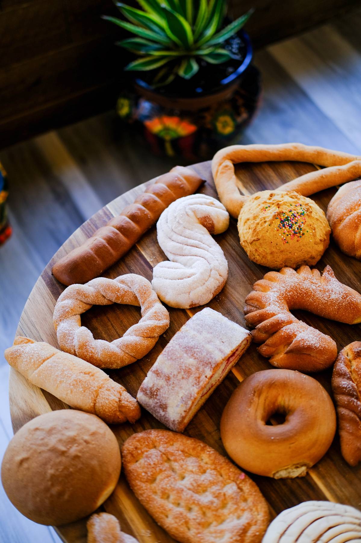 Assorted baked goods on a wooden surface, with a potted plant in the background.