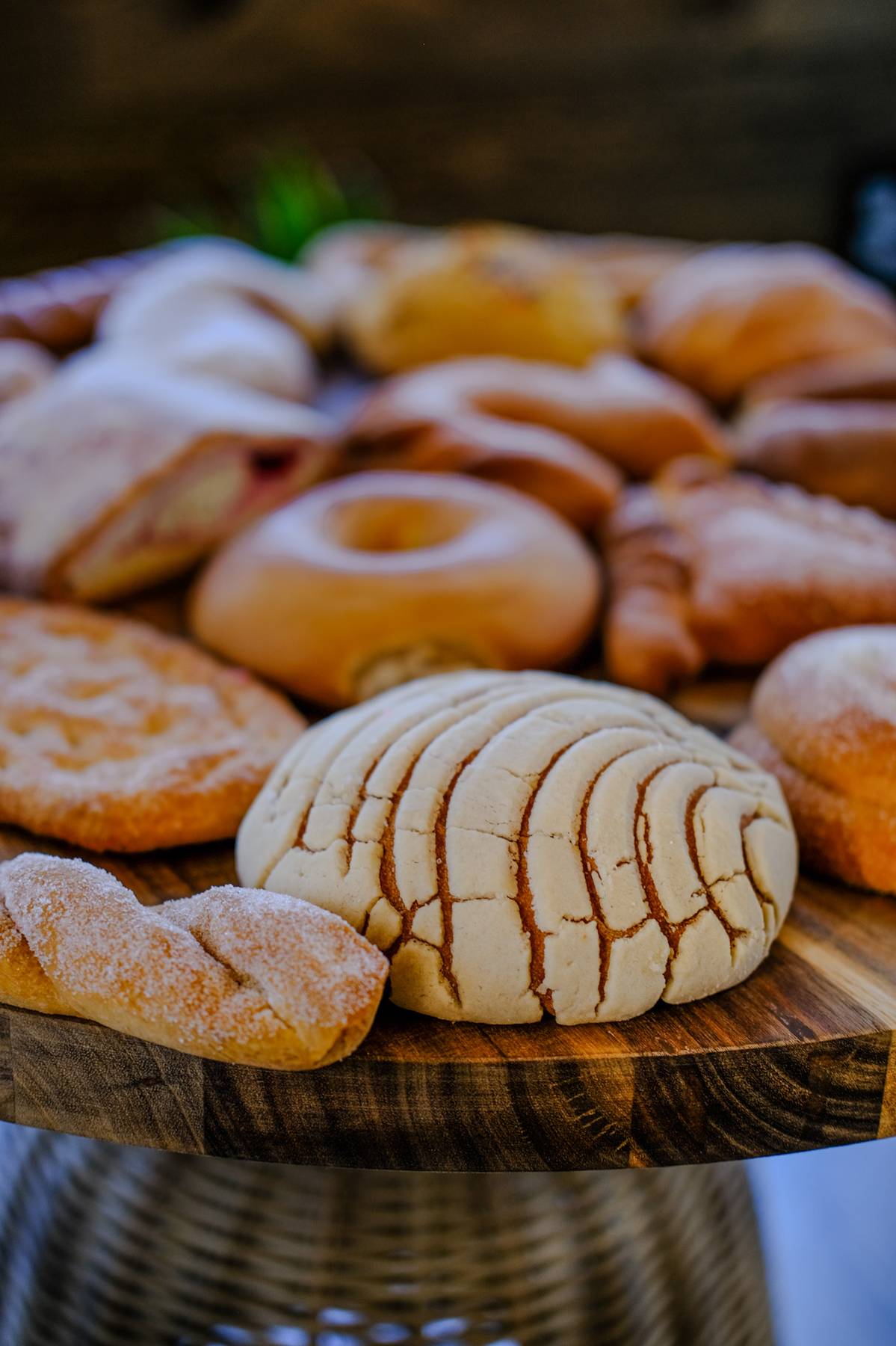 Assorted cookies on a wooden tray, some with cracks and powdered sugar, in a close-up view.