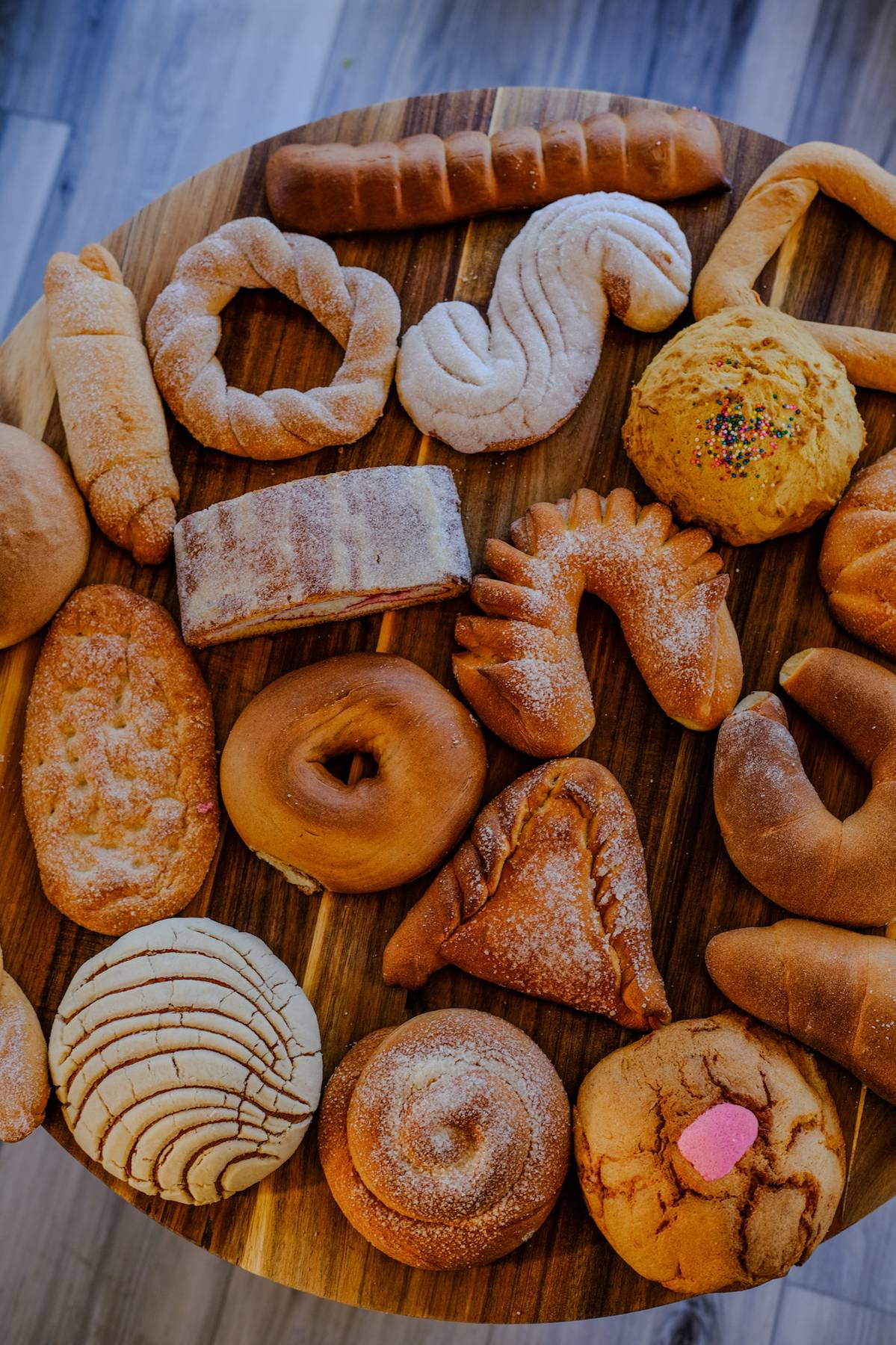 Assorted cookies and baked goods on a round wooden tray, including cookies, biscuits, and pastries.