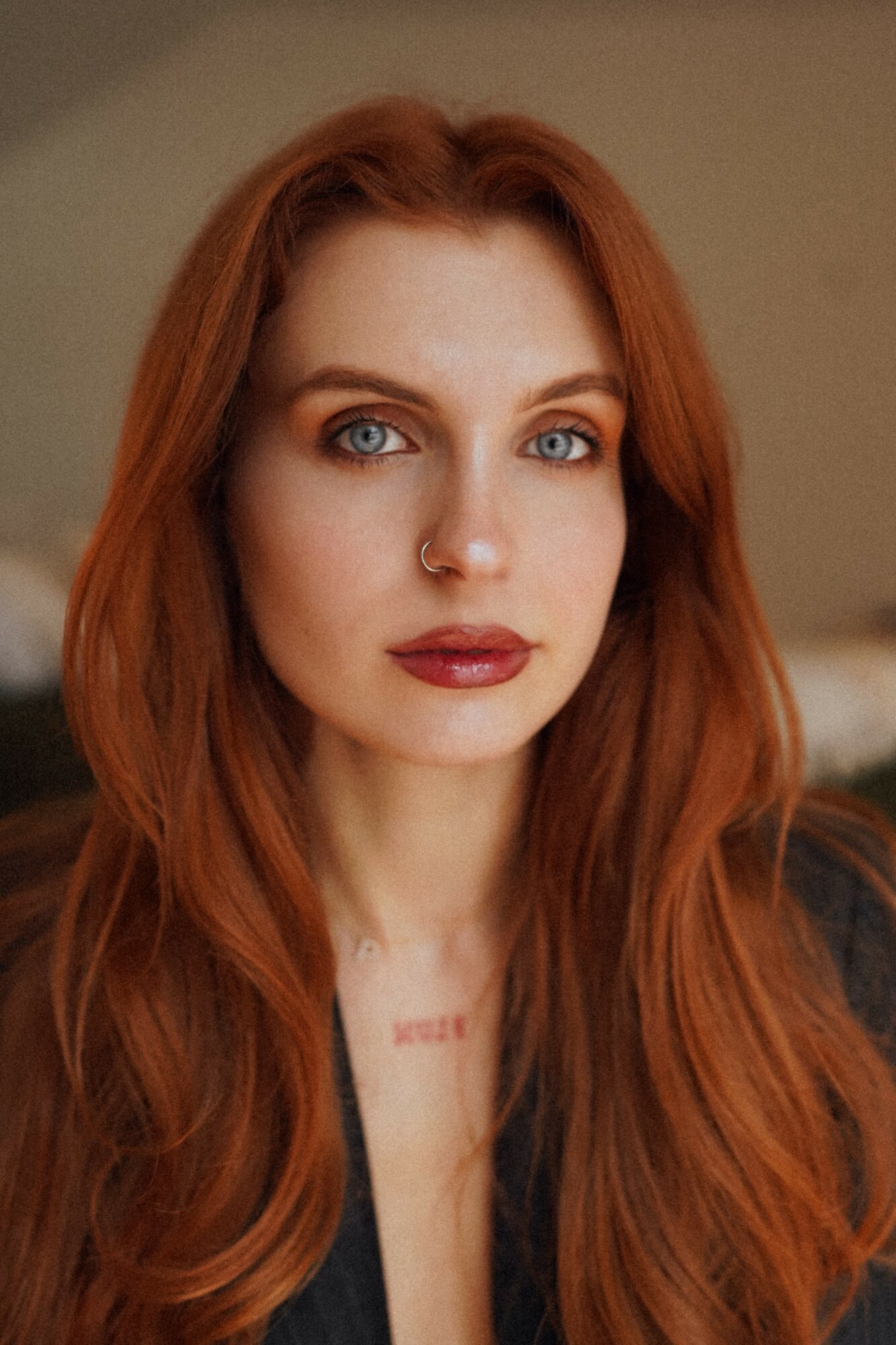 Close-up of a woman with long red hair and blue eyes, looking directly at the camera.