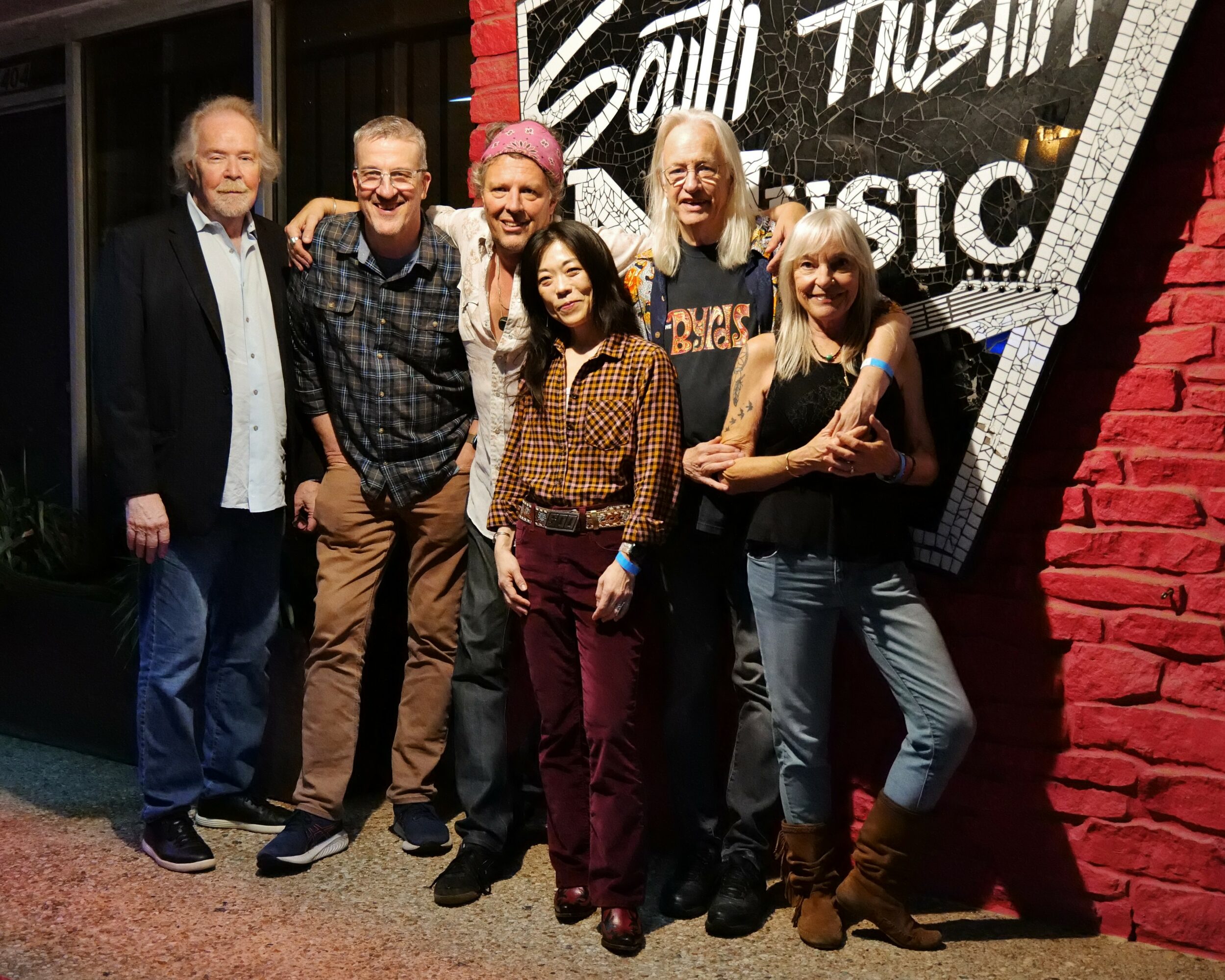 Group of six people standing together in front of a sign that reads 'Youth Music'.