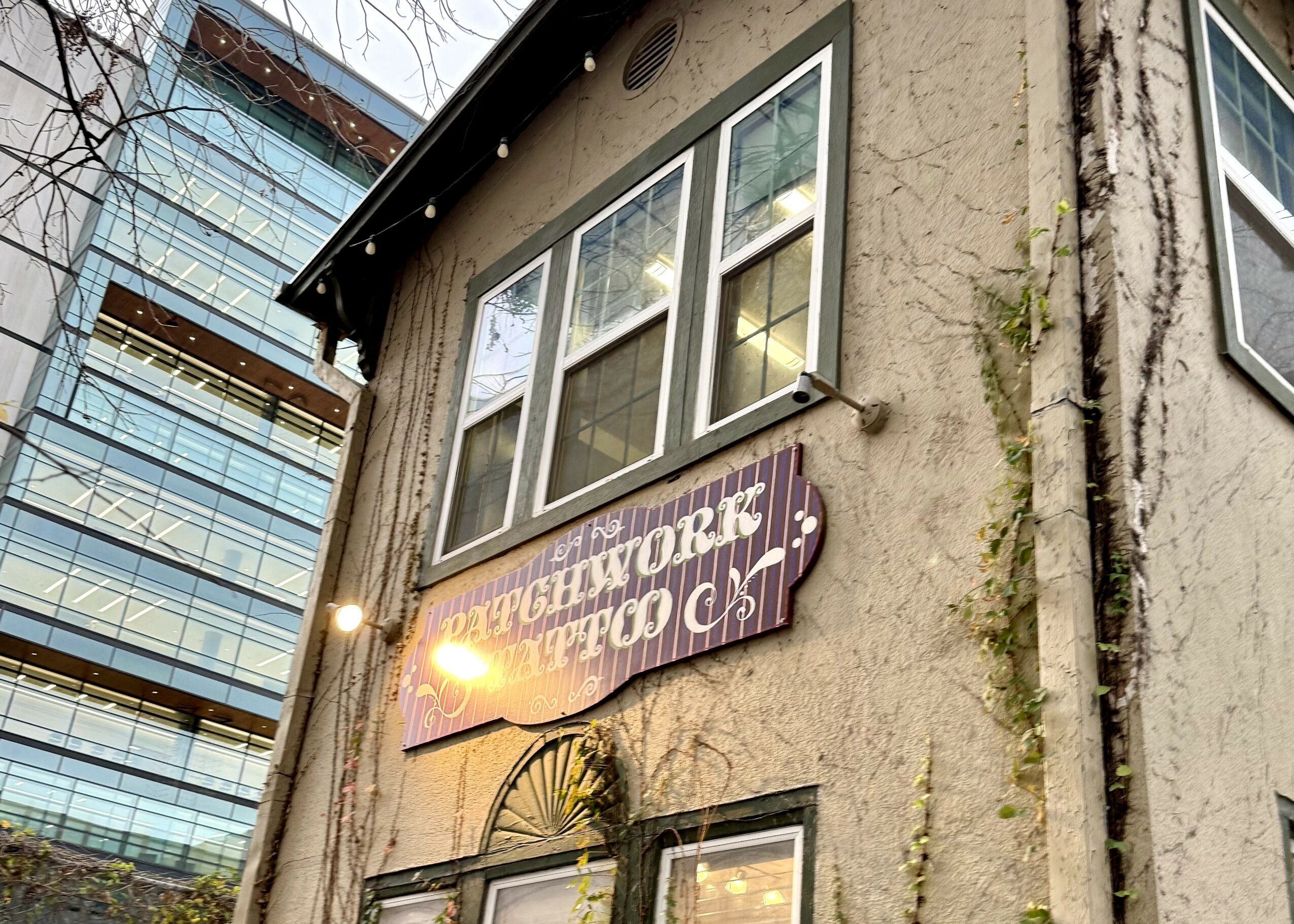 Old building with a sign, windows, and a modern glass building in the background.