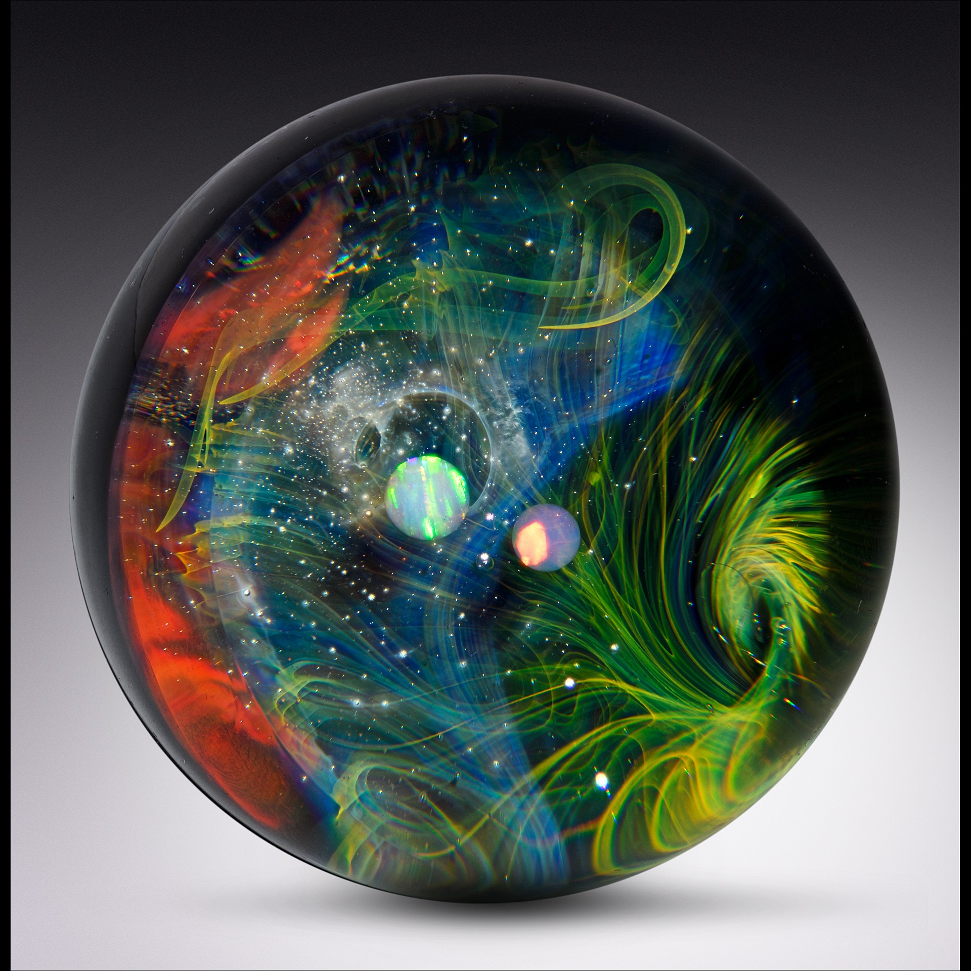 Colorful swirling patterns inside a glass sphere resembling a cosmic scene with planets and stars.