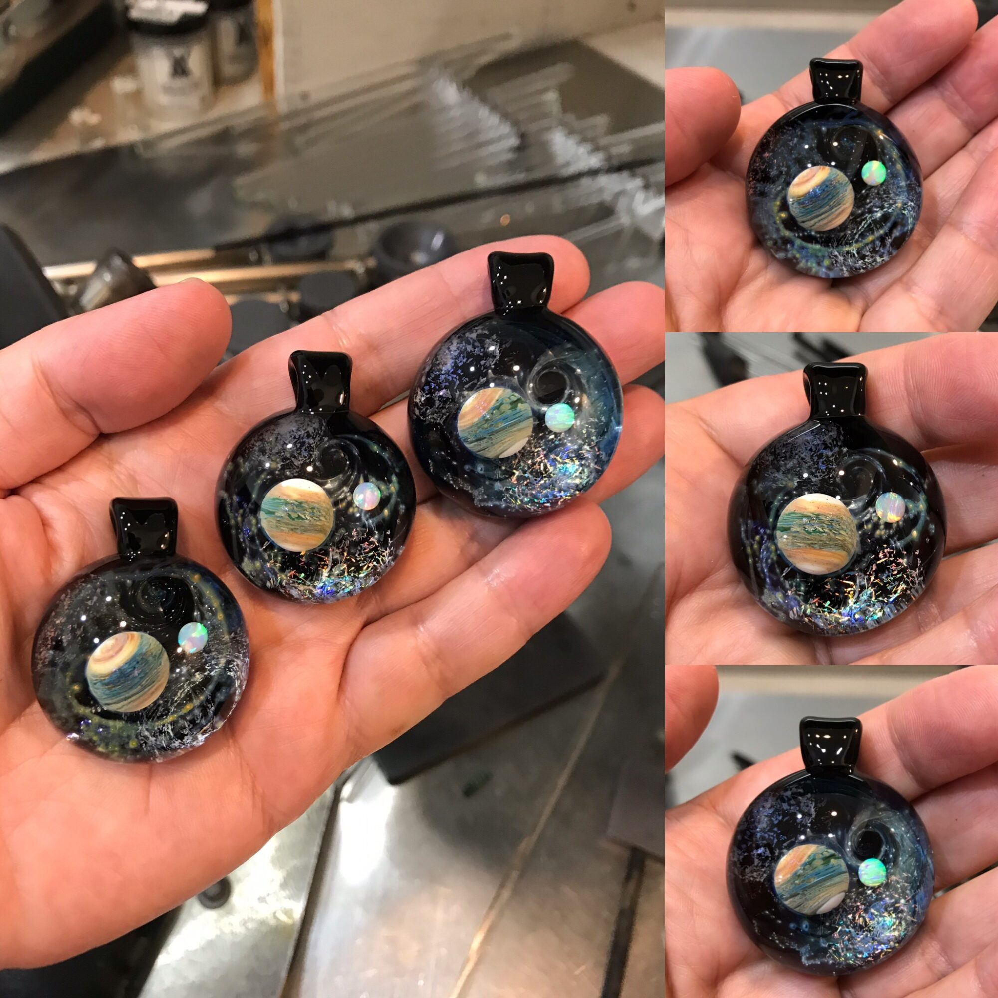 Hand holding three round pendants with galaxy and planet designs, against a kitchen background.