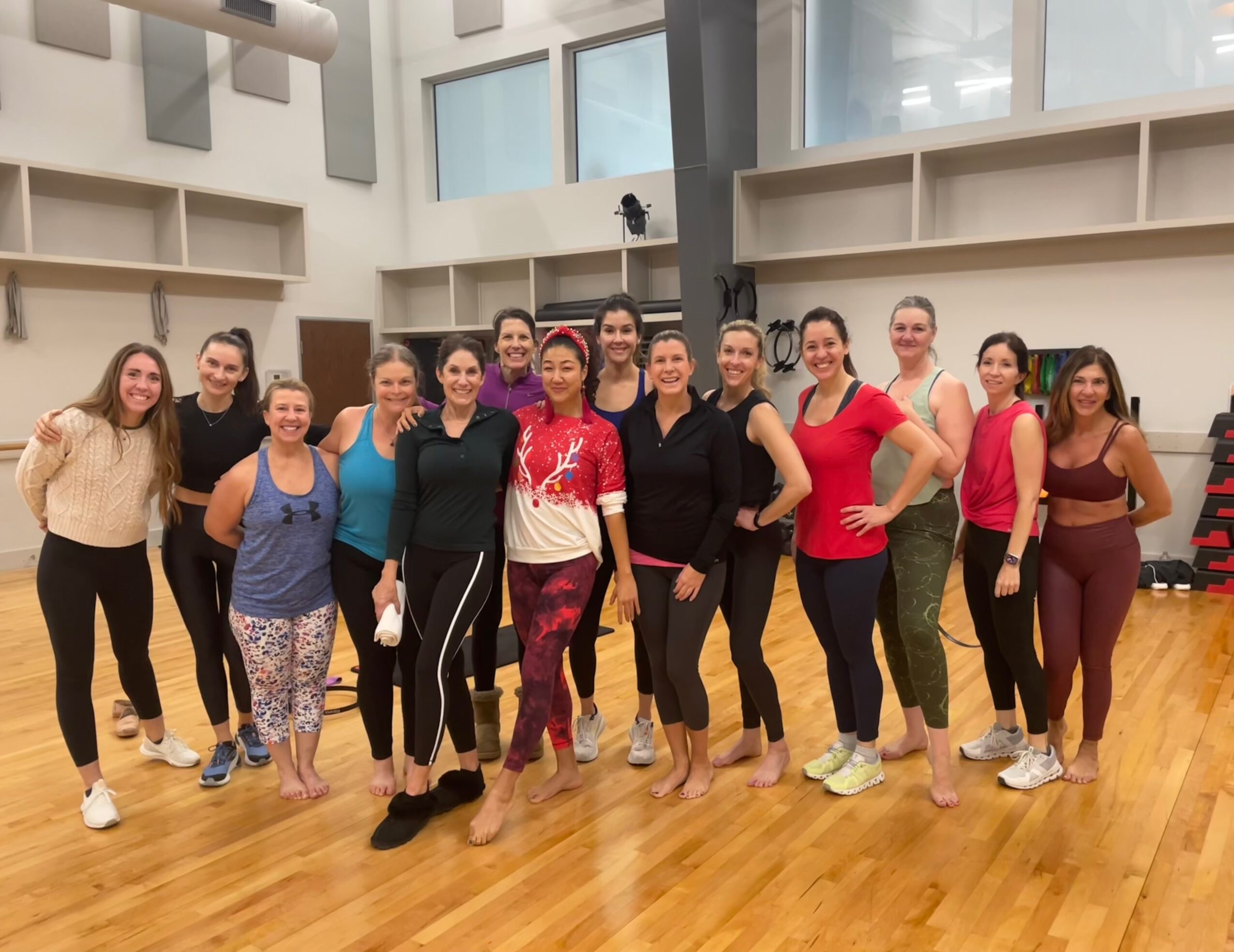 A group of people pose together in a bright indoor exercise studio.