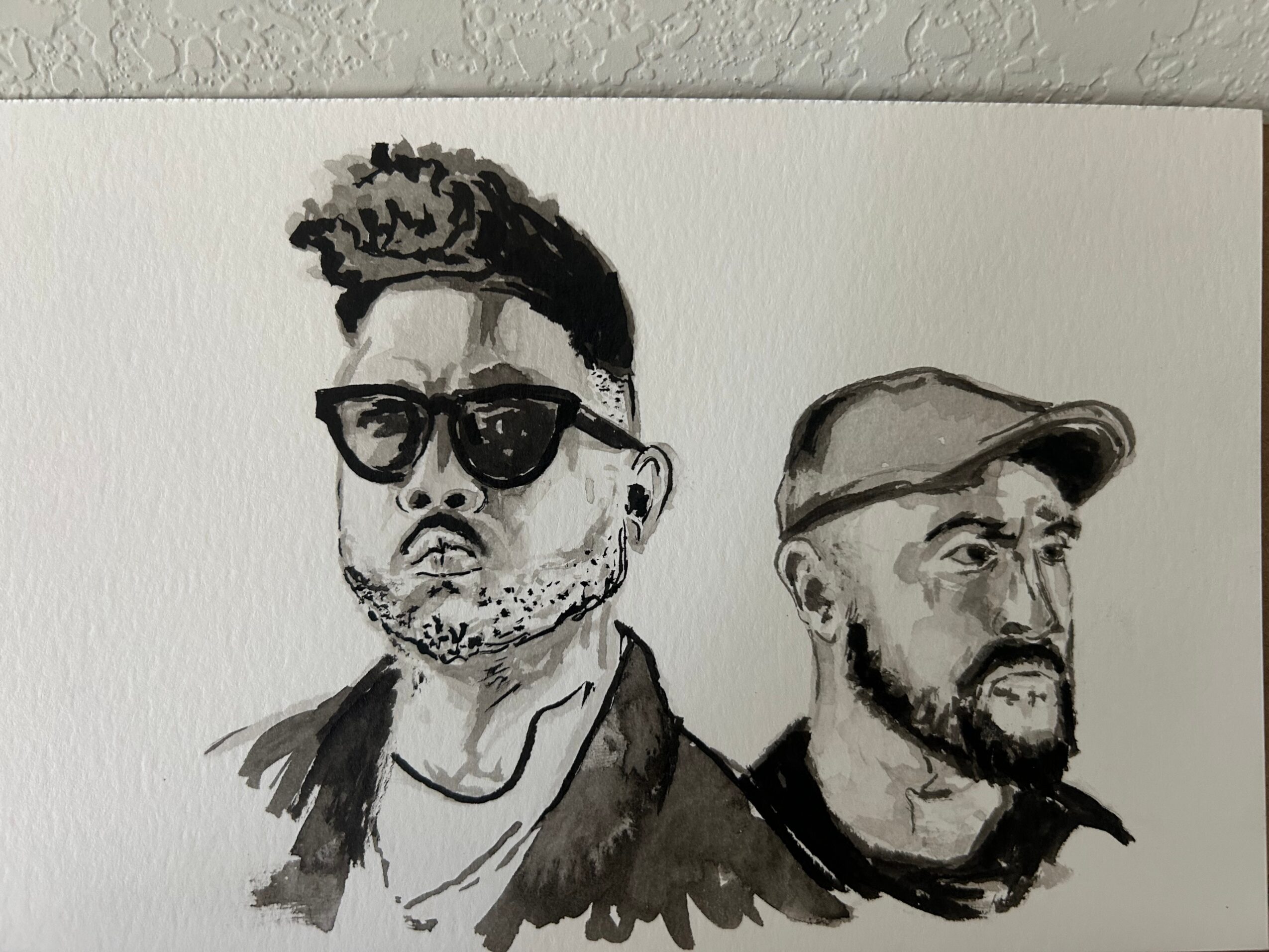 Ink portrait of two people, one wearing sunglasses and the other wearing a cap.