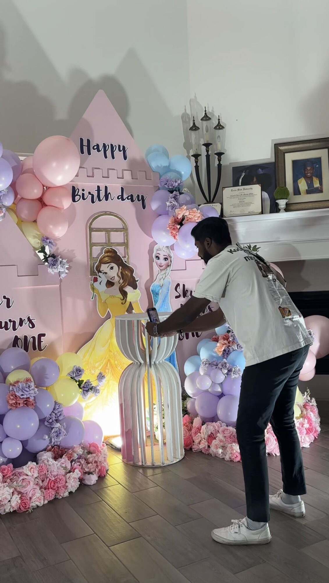 Person arranging birthday decorations with balloons and a cake, celebrating a birthday party indoors.