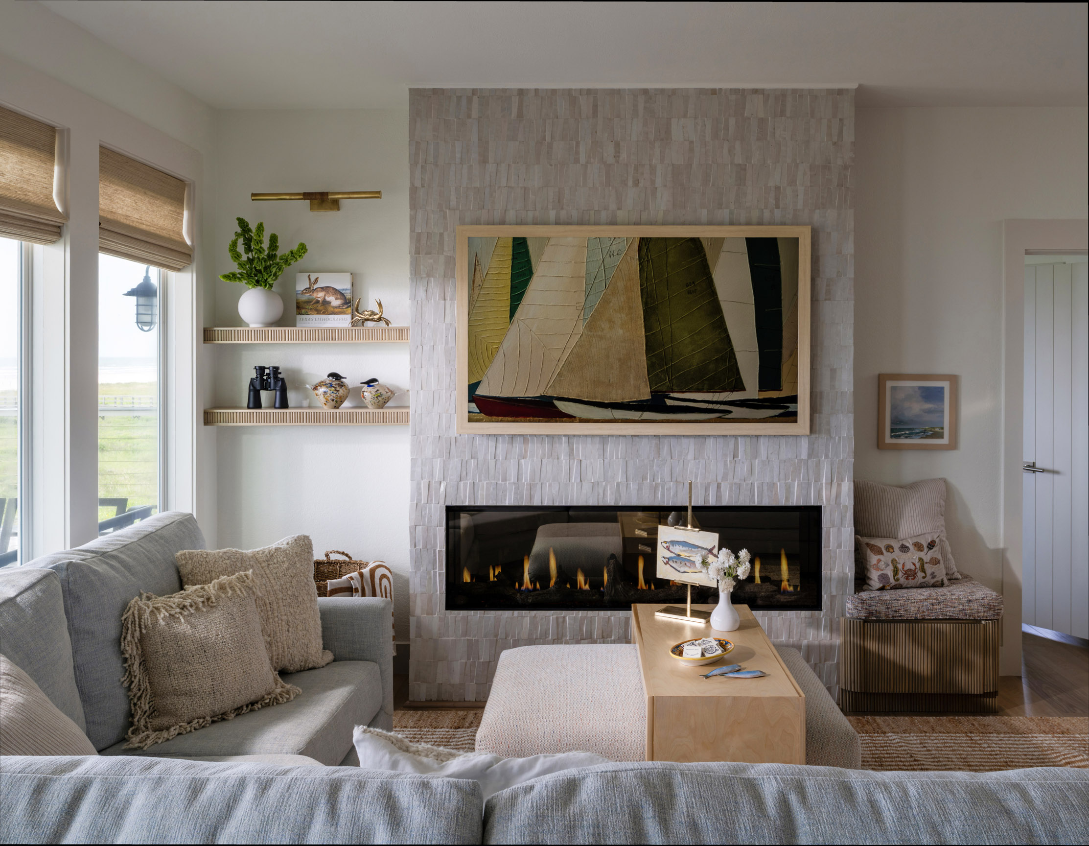 Living room with a fireplace, sofa, and wall art, with windows on the left and a door on the right.