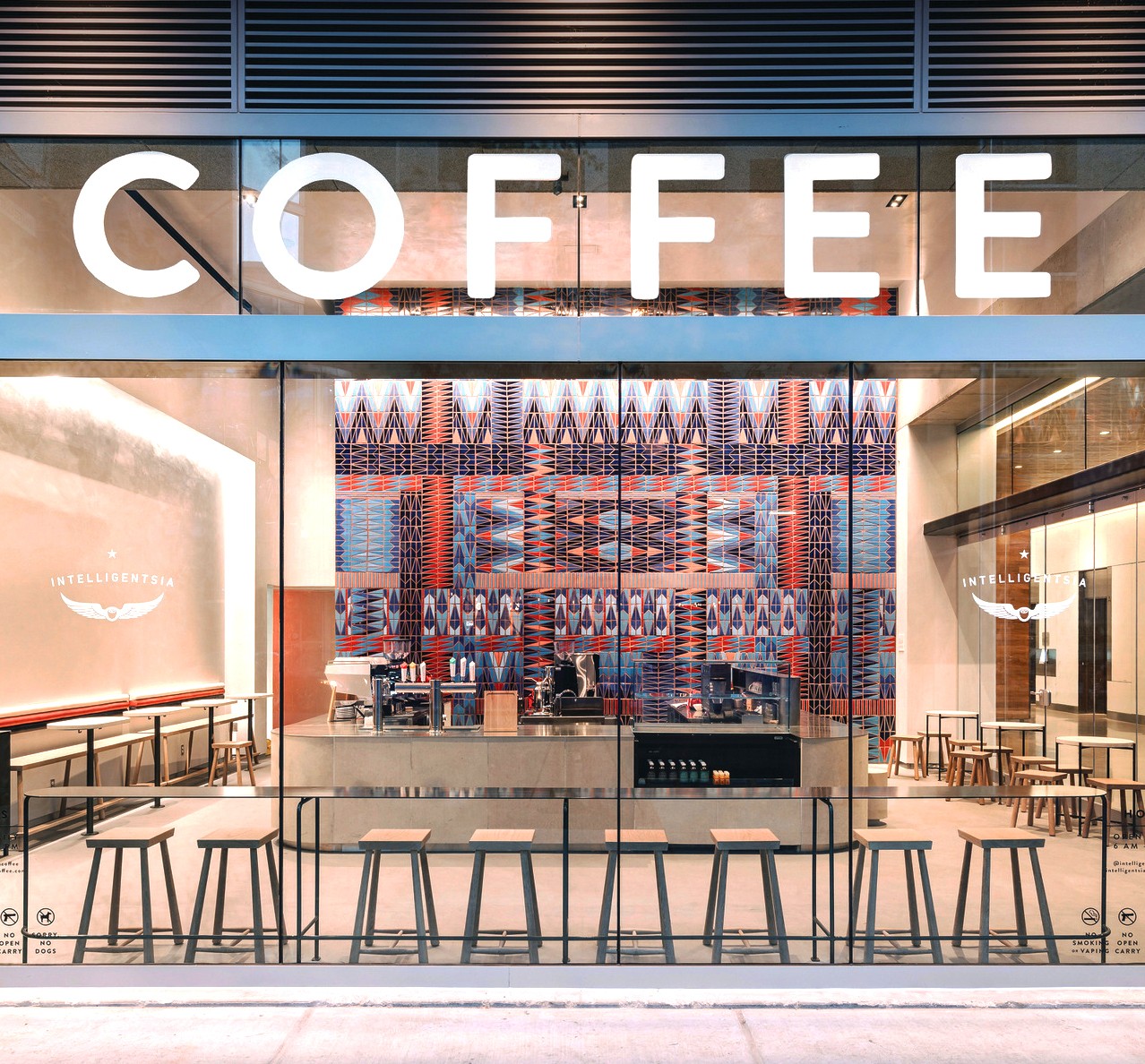 Coffee shop with large sign, colorful patterned wall, and seating area inside.