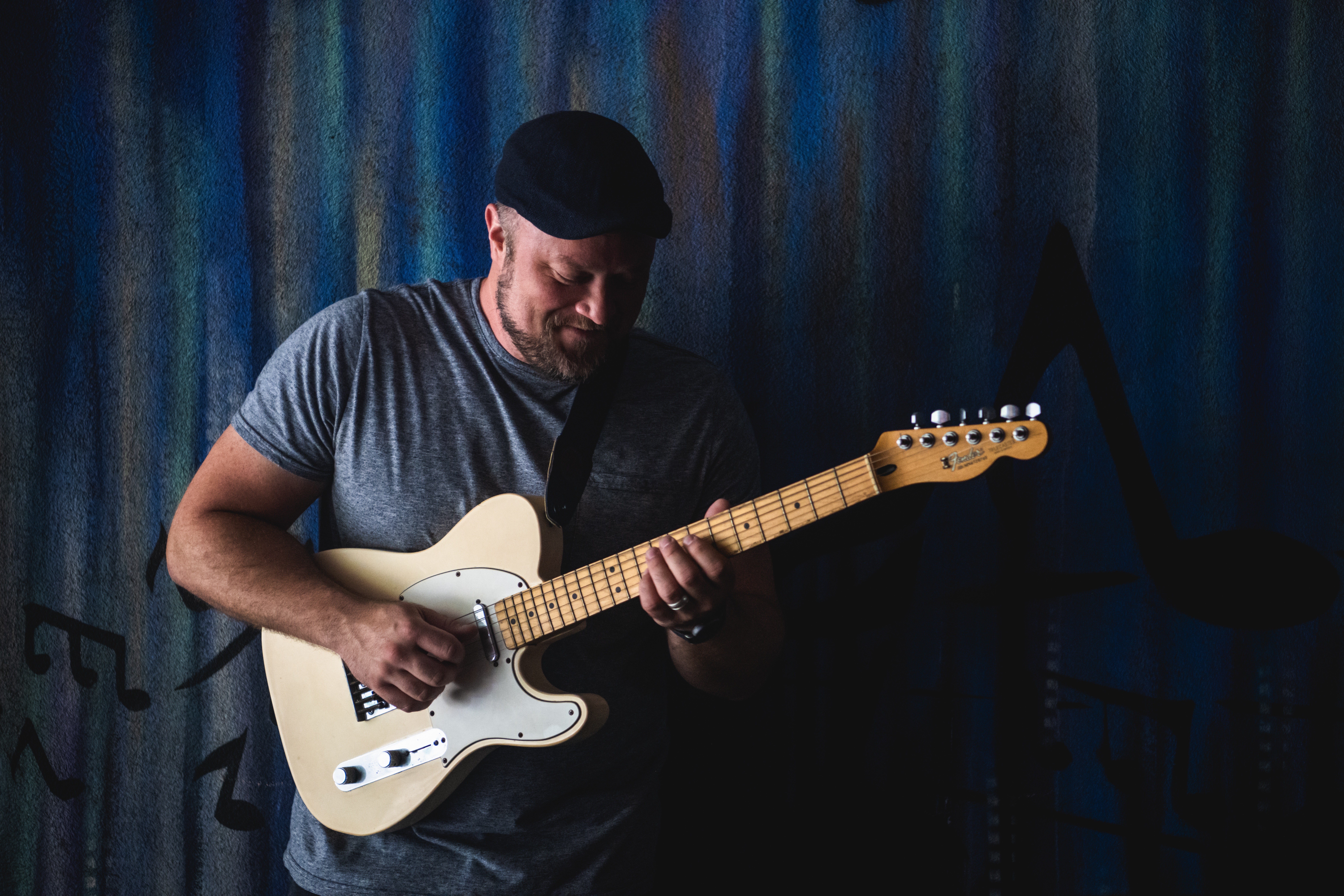 Person playing an electric guitar on stage with a dark background.
