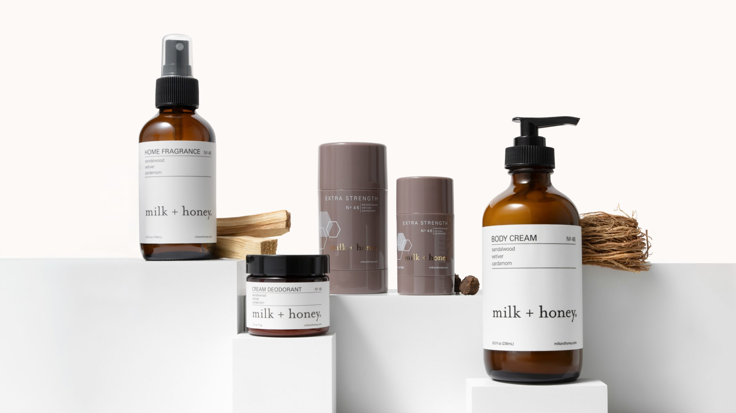 Several milk + honey skincare bottles and jars displayed on white shelves.