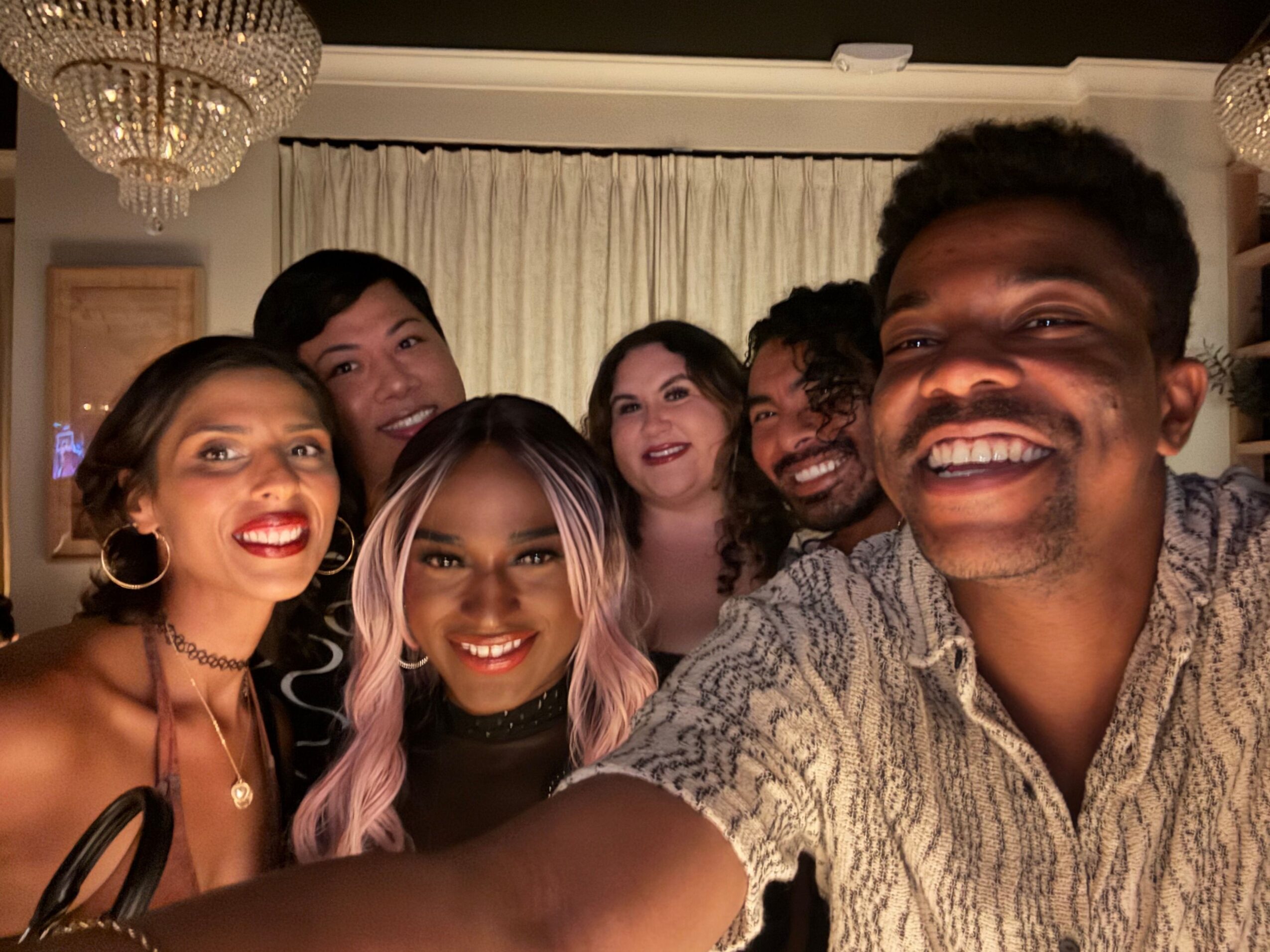 Five people pose closely together indoors, smiling toward the camera.