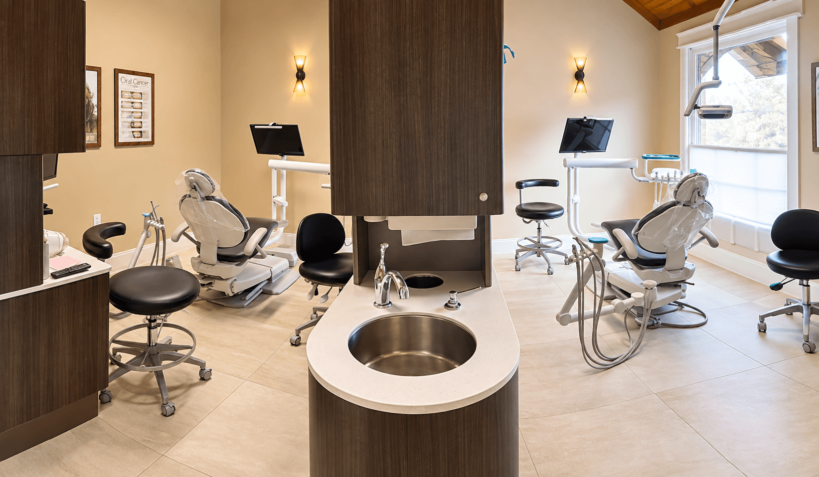 A bright dental clinic with treatment chairs, stools, equipment, and a central round counter.