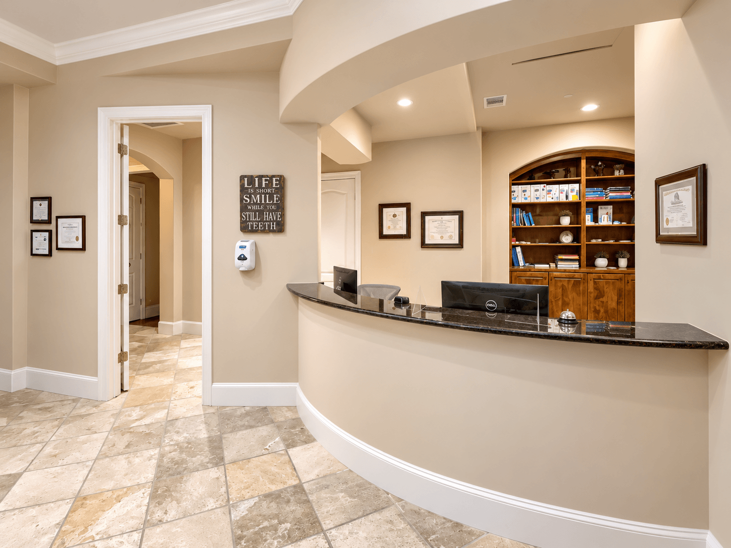 Curved reception desk beneath an arch, with a hallway, tiled floor, wall signs, and wooden shelving behind it.