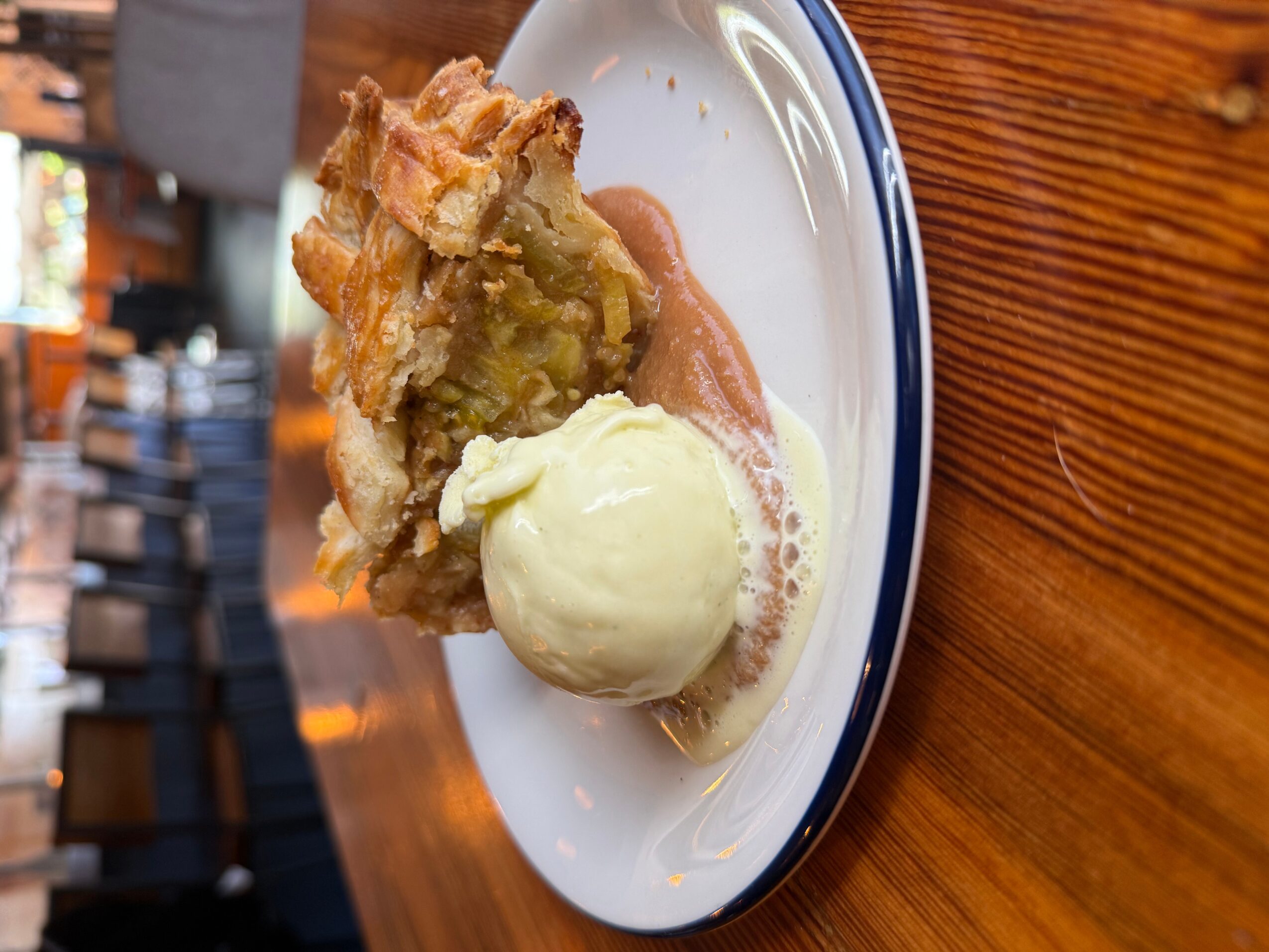 A scoop of vanilla ice cream beside a piece of fruit pie on a white plate.