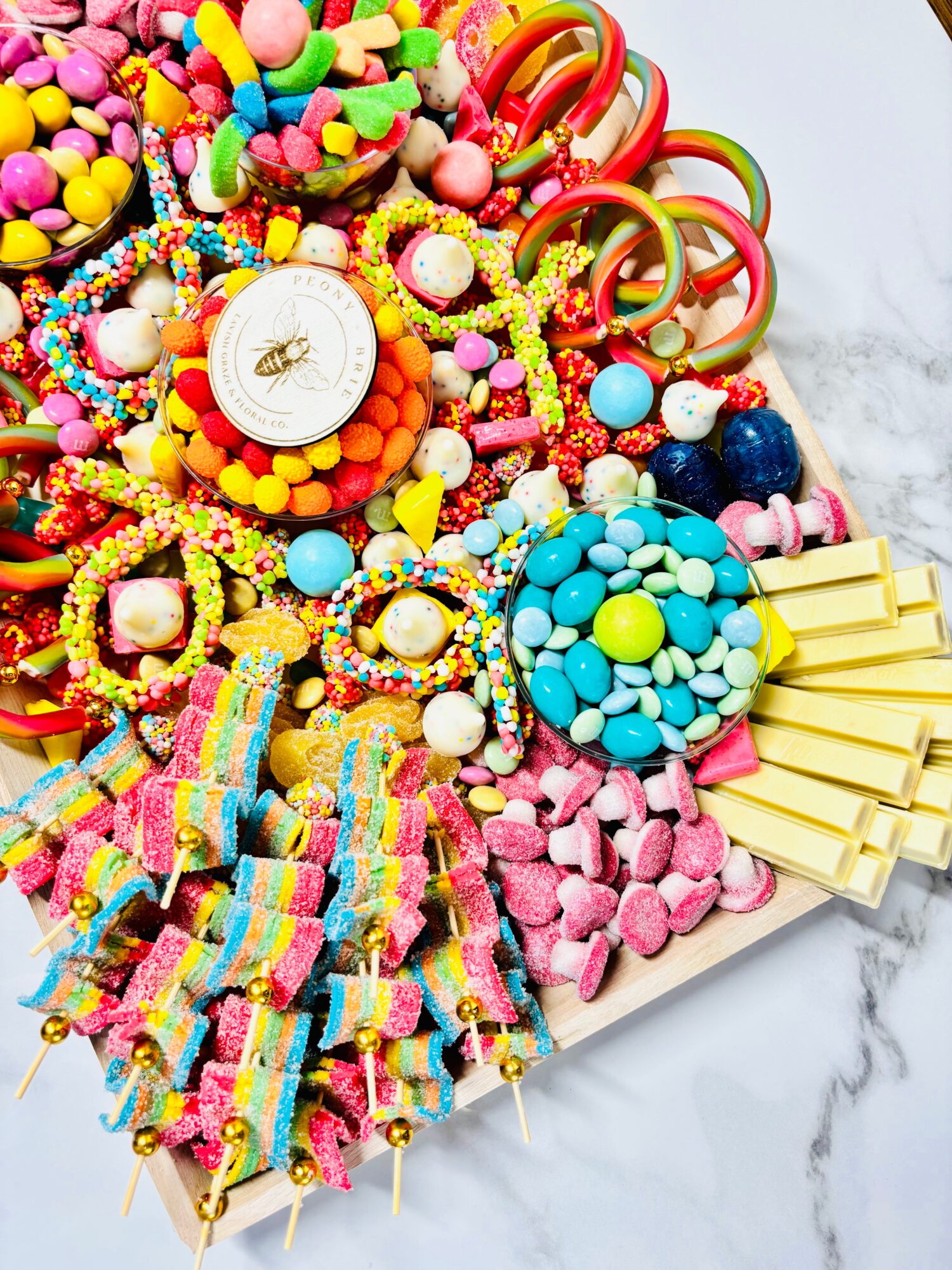 A tabletop covered with colorful candies, lollipops, sweets, and a small clock.